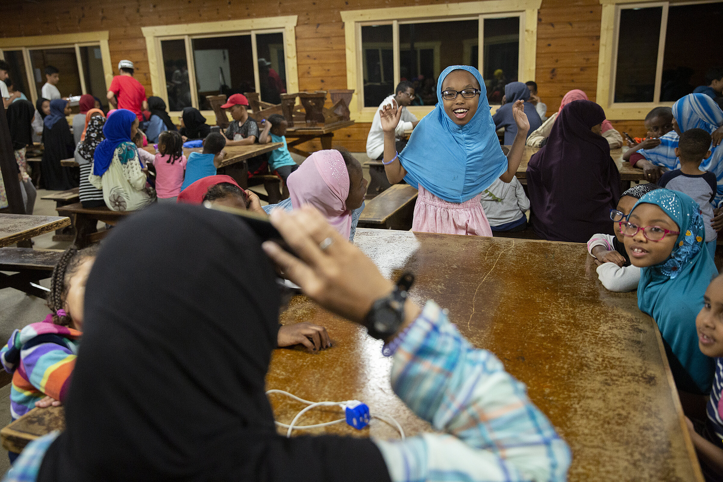  Hanan Samatar (center) mimics a bird during a game of charades in the dining hall before dinner.  More than 75 kids and their family members spent five days at this year's Youth and Family Circle summer camp. 