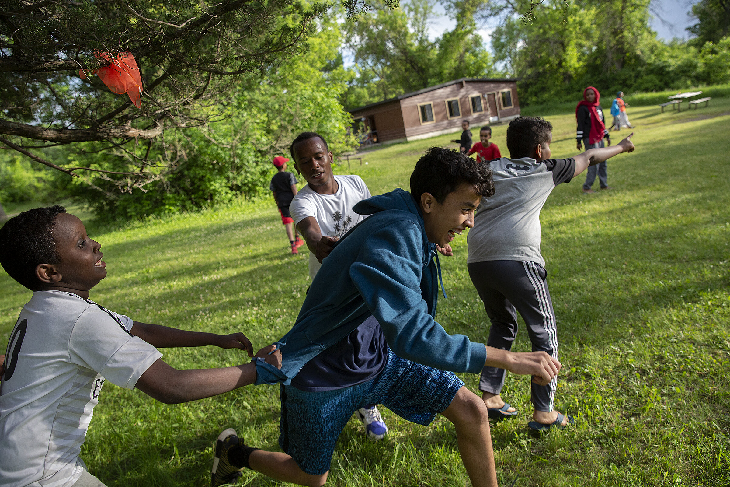  A Minnesota summer camp is helping connect city kids and children of refugees to the state's outdoor summer culture, often for the first time. Khalid Musse (left) and  Abubakar Sherif (center) grab Bukhari Booker during a game of capture the flag at