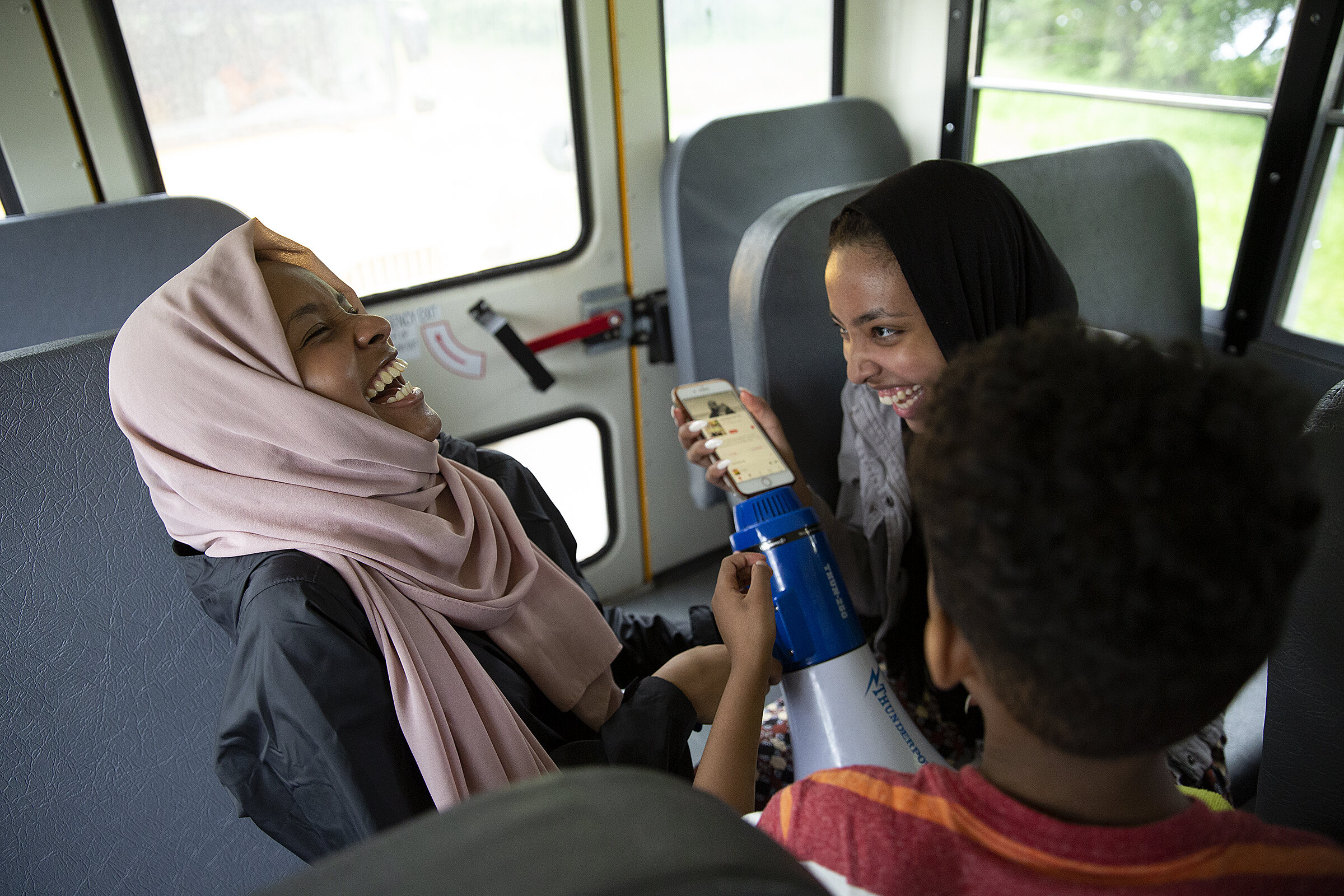  From left, Hafsa Musse, 15, and Bayaan Booker, 18, play music over the megaphone during a bus ride in New London, Minn.  