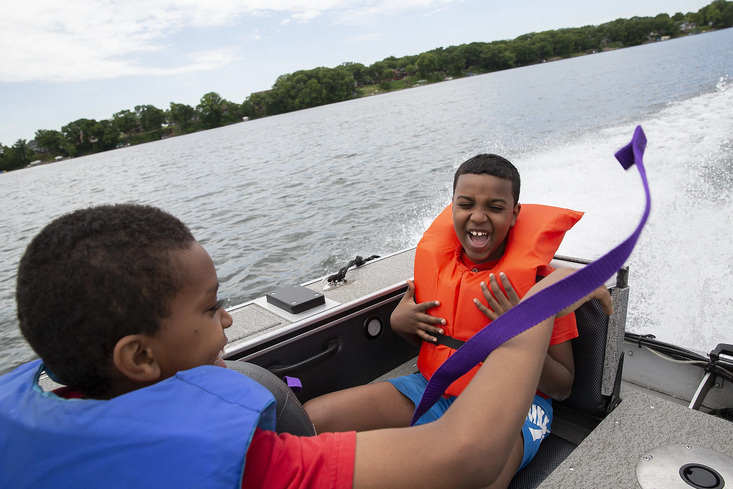  From left, Luqman Yusuf and Abdirahmen Adam laugh as they encourage Sgt. Michael Tombaga of the Ramsey County Sheriff's Office to drive the boat faster. Abdirahmen says camp has helped him become a better person by allowing him to try new experience