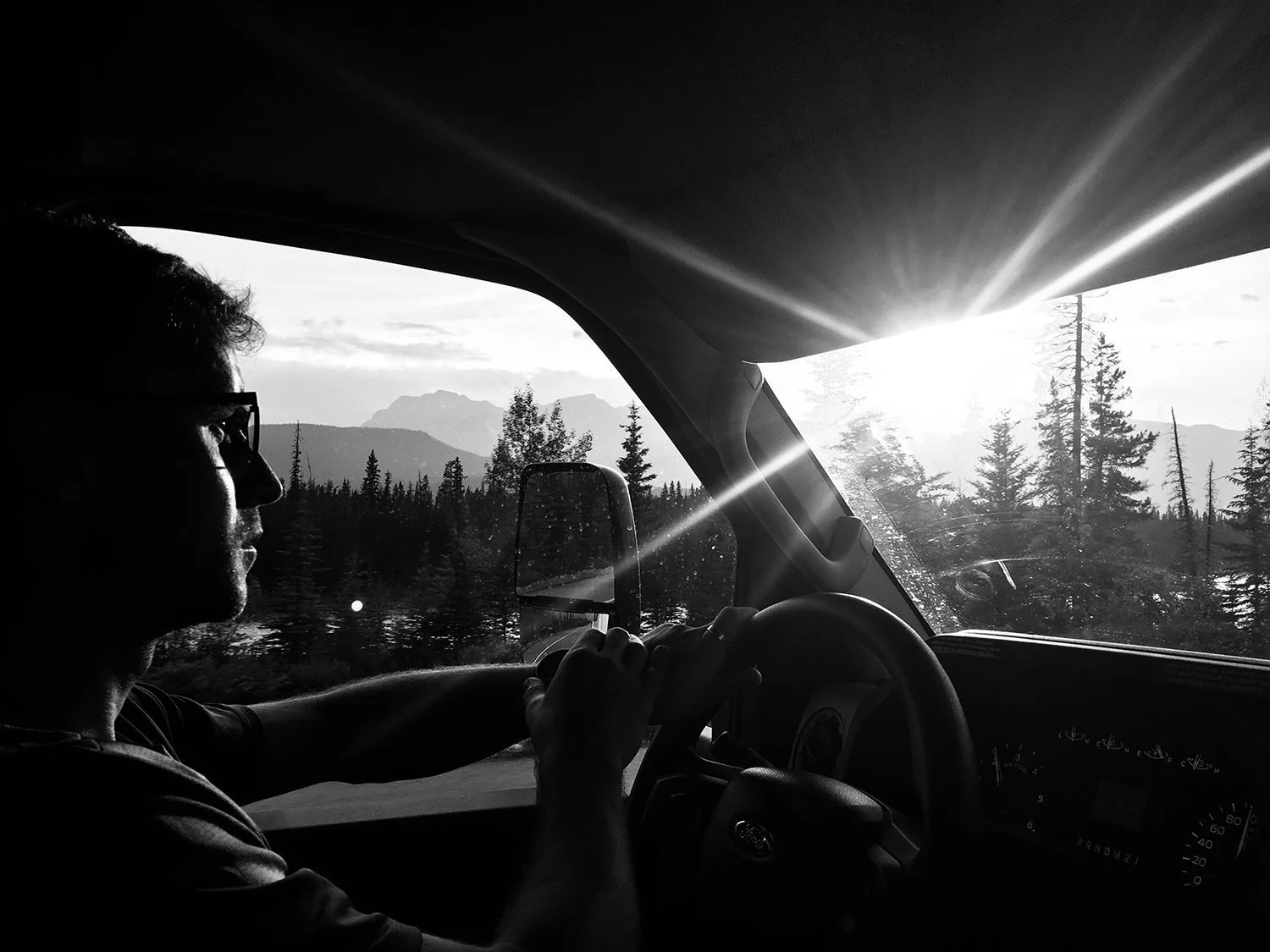 man+looking+out+of+window+while+driving+with+sun+flare+and+mountains+in+the+background+by+Nathaniel+Rosa+shot+on+iphone.jpg