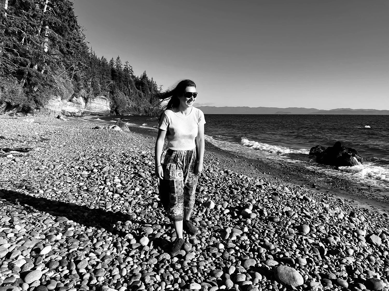 female+walking+along+pebbly+beach+looking+out+to+sea+in+black+and+white+by+Nathaniel+Rosa+shot+on+iphone.jpg