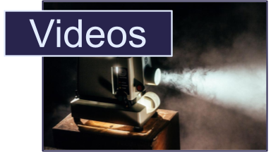 Old school video projector in a dark room. The word Videos is overlayed in the top left.