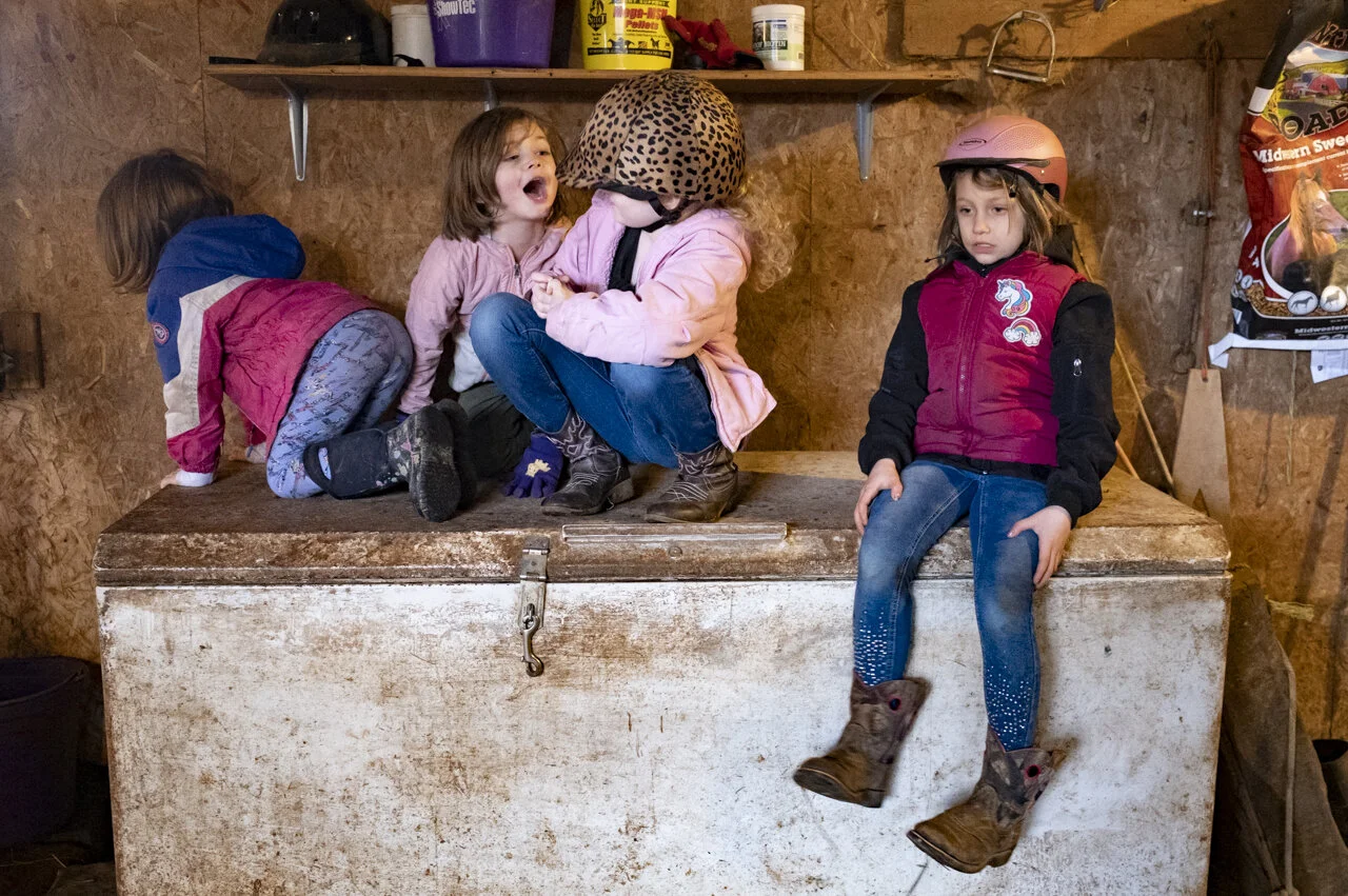 Kenna Sayre, 3, left, Elli Sayre, 5, Nicole Whaley, 10, and Gwen Sayre, 7, play on top of a freezer that has been converted into a storage container for horse feed, while Heidi and Amy Whaley finish feeding the horses in Shade, Ohio.