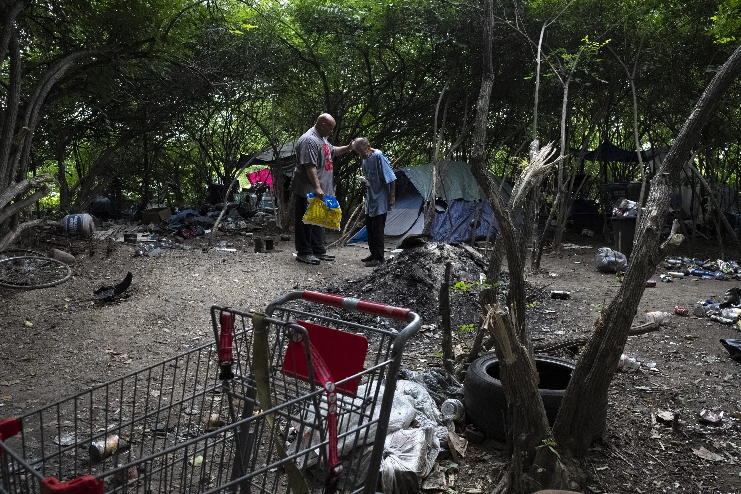  Todd Penn, left, says a prayer for Papa Bear, who preferred not to provide his legal name, after giving out supplies and food to a homeless camp in southern Columbus on Aug. 27, 2022. Penn is frequently accompanied by his wife, and gives out food an
