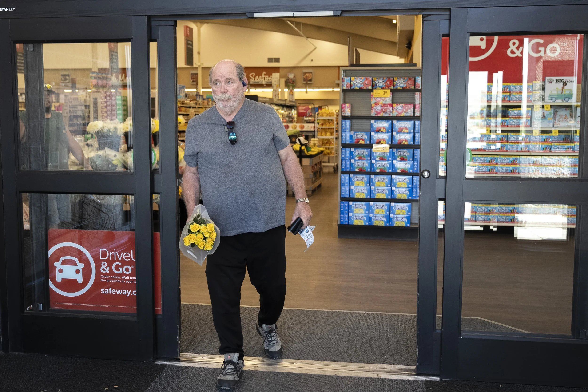  Carrying yellow flowers for Lynne, her favorite color, Wayne leaves the grocery store to drive home to celebrate the anniversary of the day they met. 