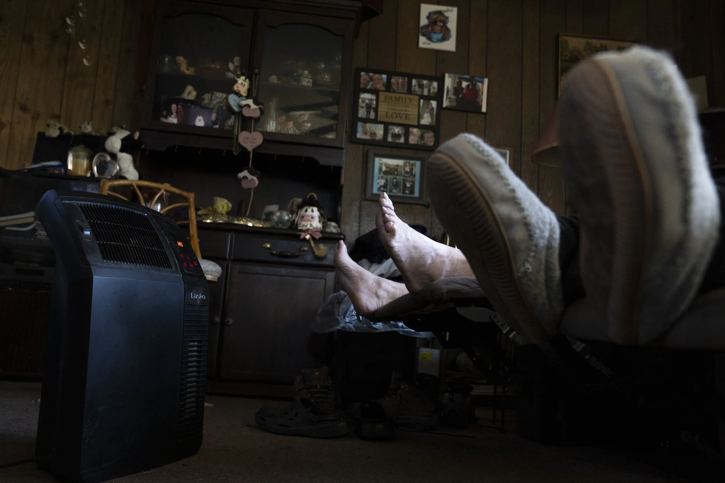  A barefoot Wayne relaxes next to Lynne in their recliners with two heaters set to ‘HI’ near their feet. As Lynne aged, she had increasing difficulty staying warm and even wearing multiple layers she would still shiver. 