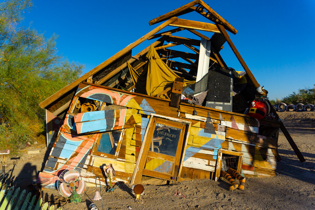 A dilapitated house art installation in East Jesus, Slab City. Notice striped stocking legs coming out of the bottom right window - a tribute to The Wizard of Oz and not being in Kansas anymore!