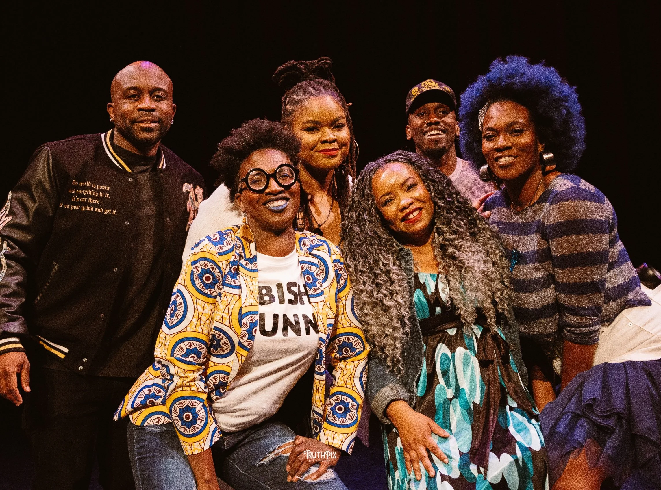 A group of comedians smile at the camera.