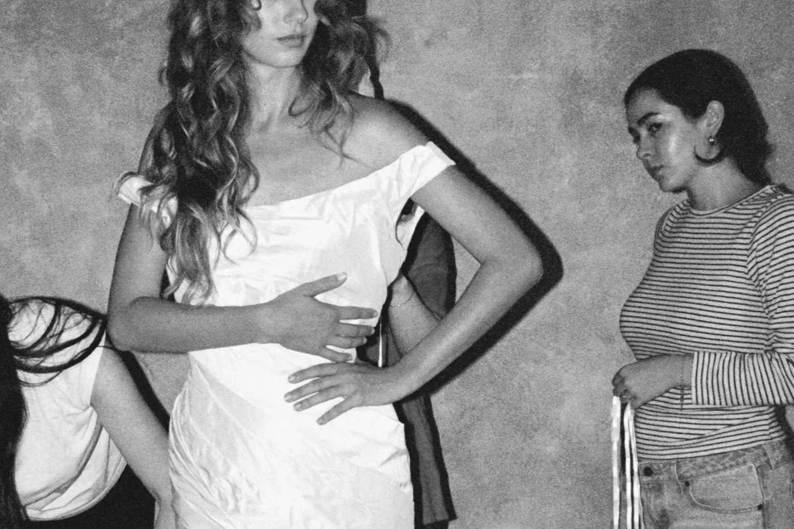 White open-toe heel with ankle strap on wooden floor with white draped wedding dress.