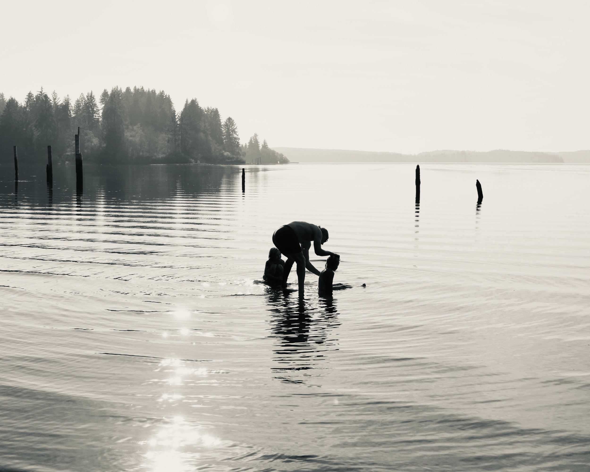 Silhouette of family playing in Lake Quinault Wa.