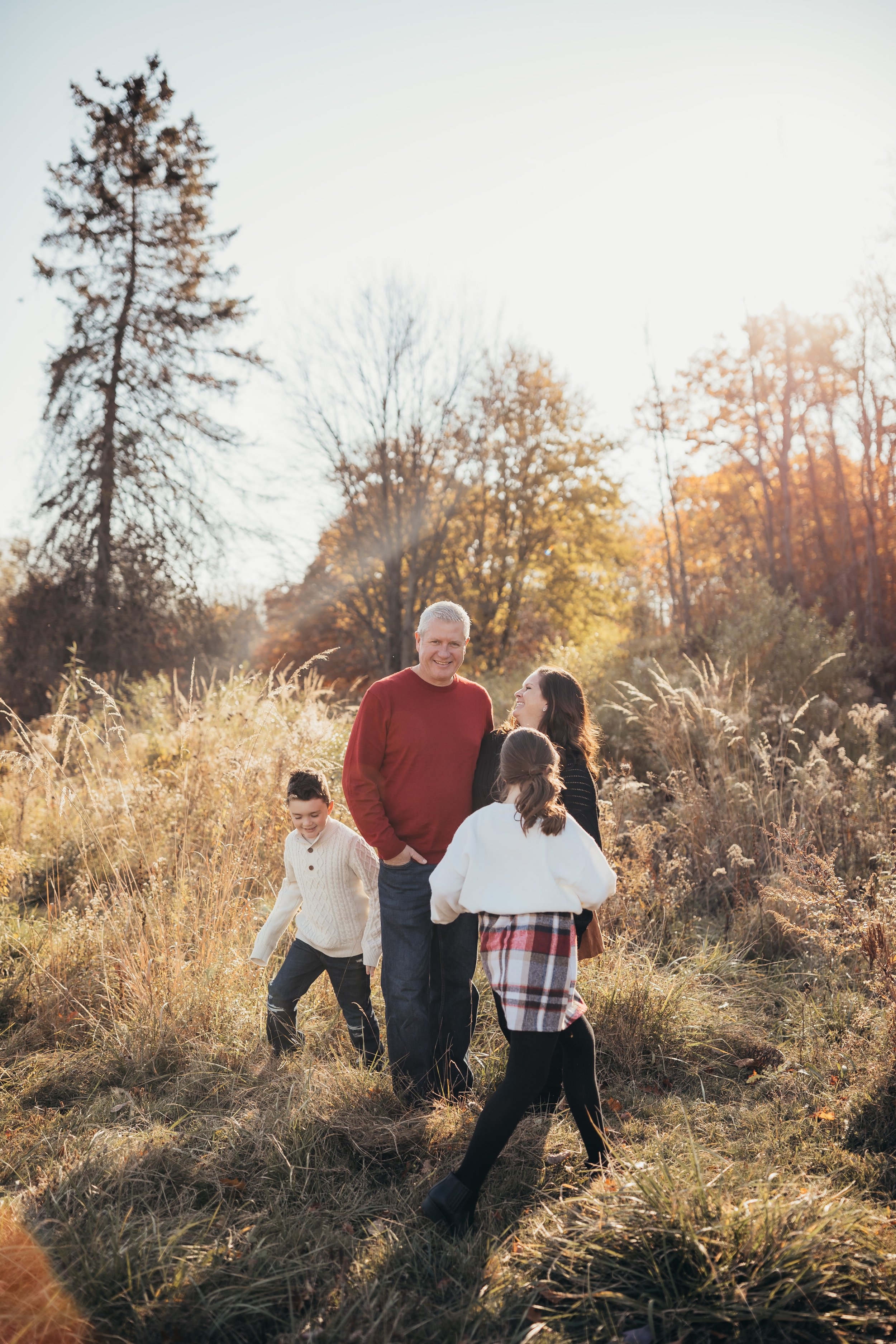 Candid family photography session with vibrant fall colored field during golden hour in Rochester NY
