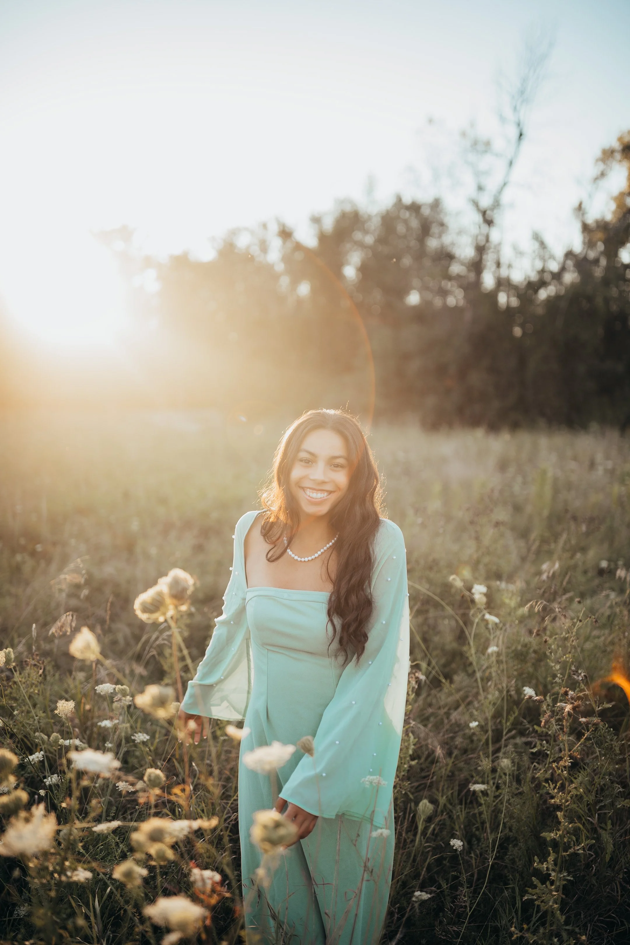 Senior portrait session in a grassy flower field during golden hour