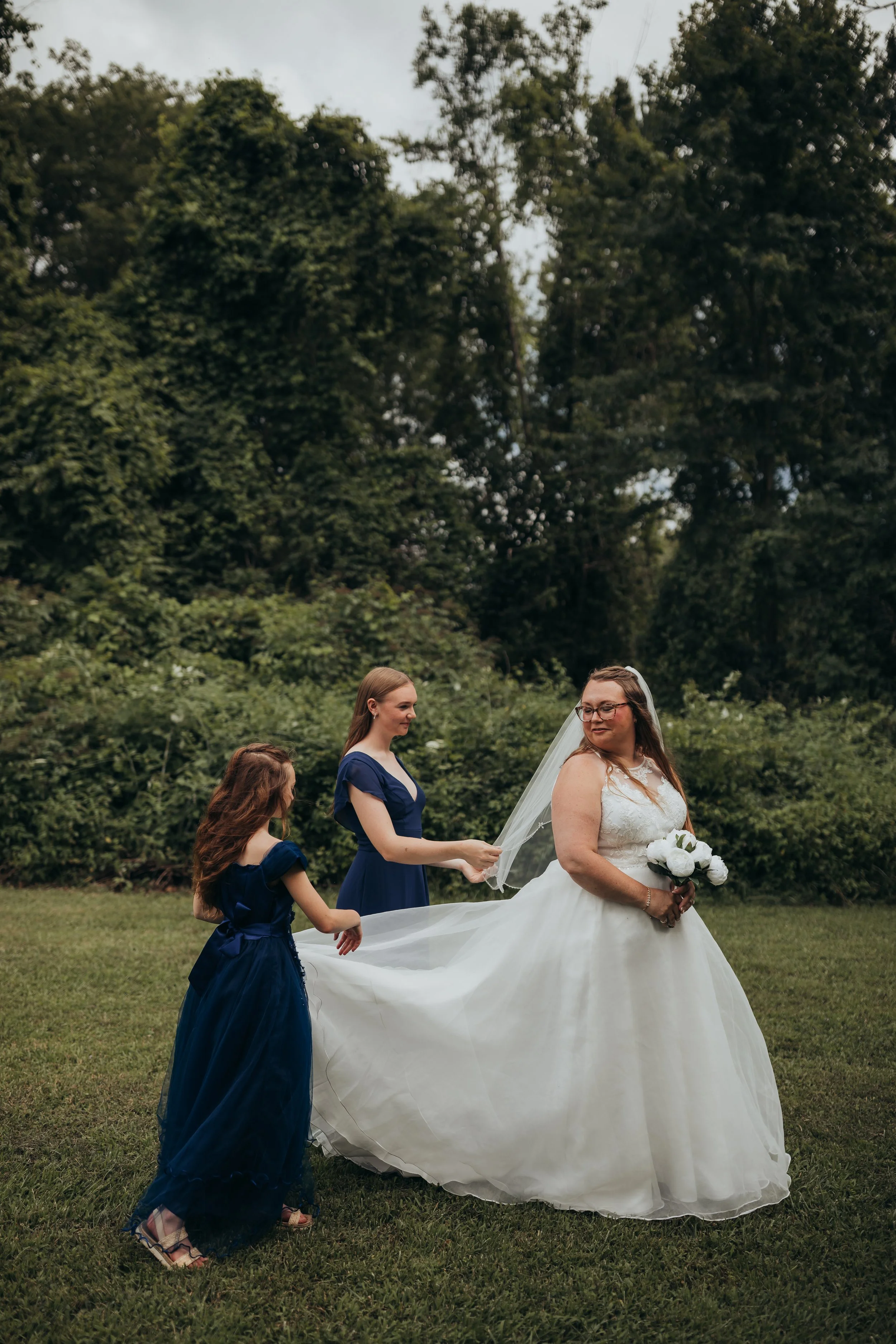 Photo of a bride looking back at her daughters behind her getting ready to walking down the aisle.