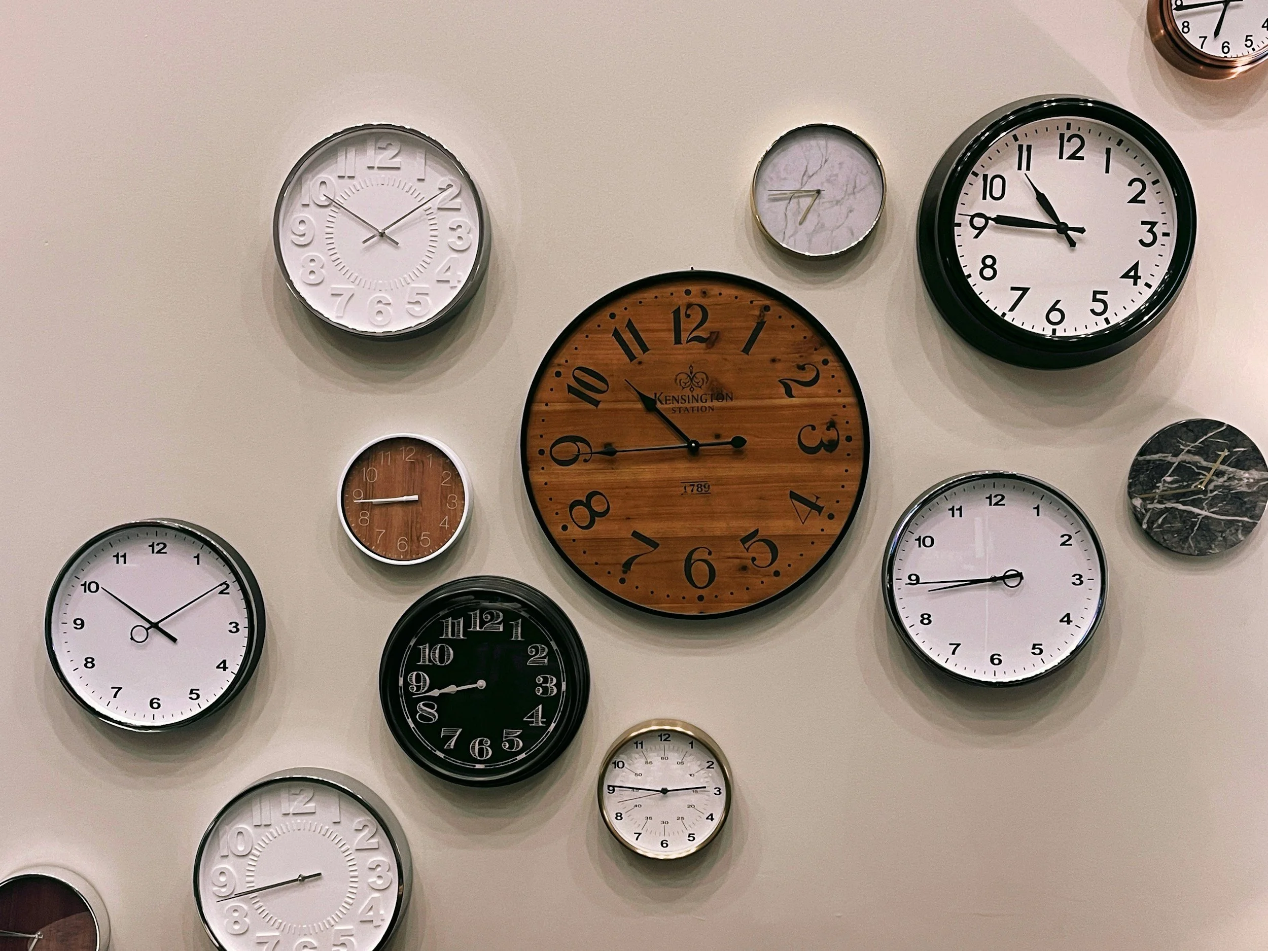A wall decorated with various clocks showing different times.