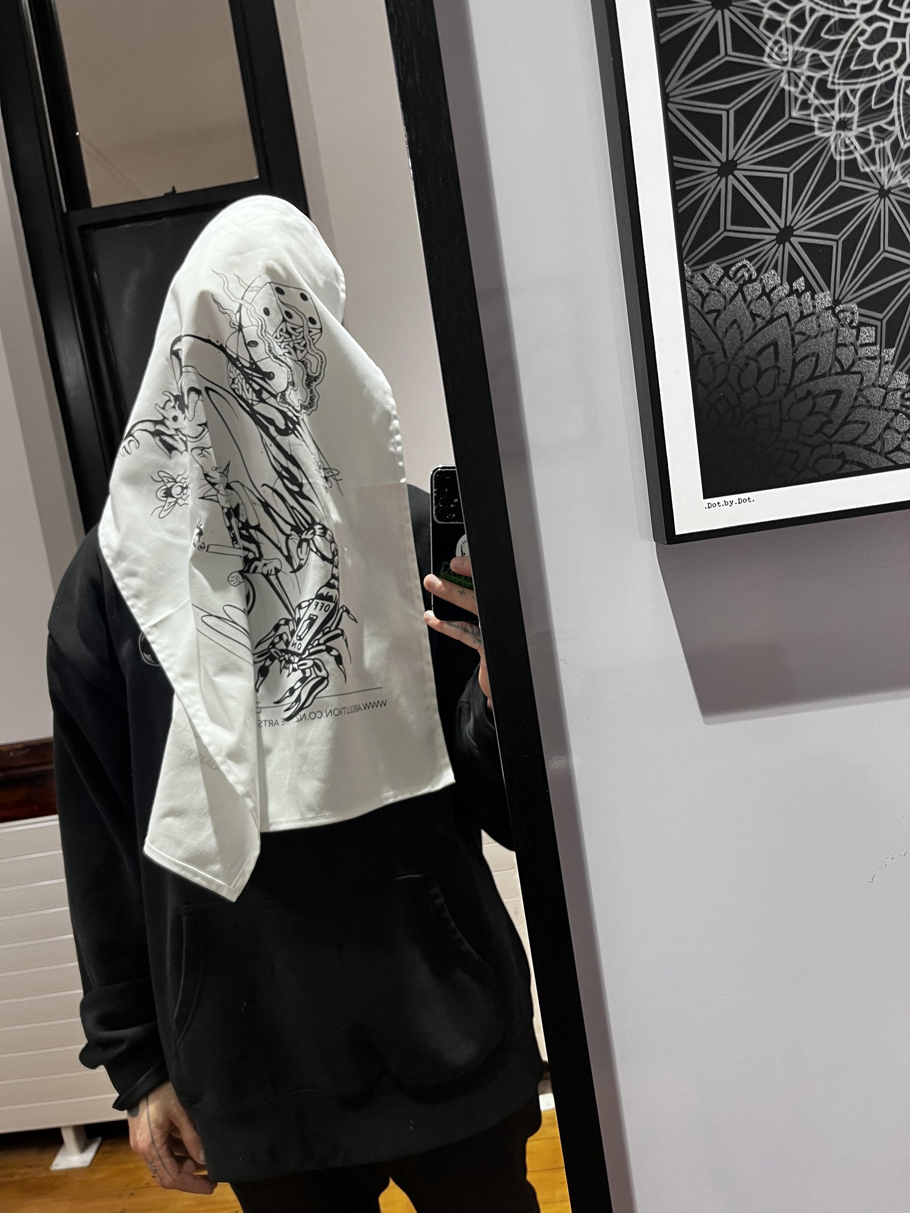 Artist mirror selfie with Absolution Tattoo Studio tea towel draped over head – screen-printed cotton towel showcasing flash collage designs from Christchurch-based tattoo artists.