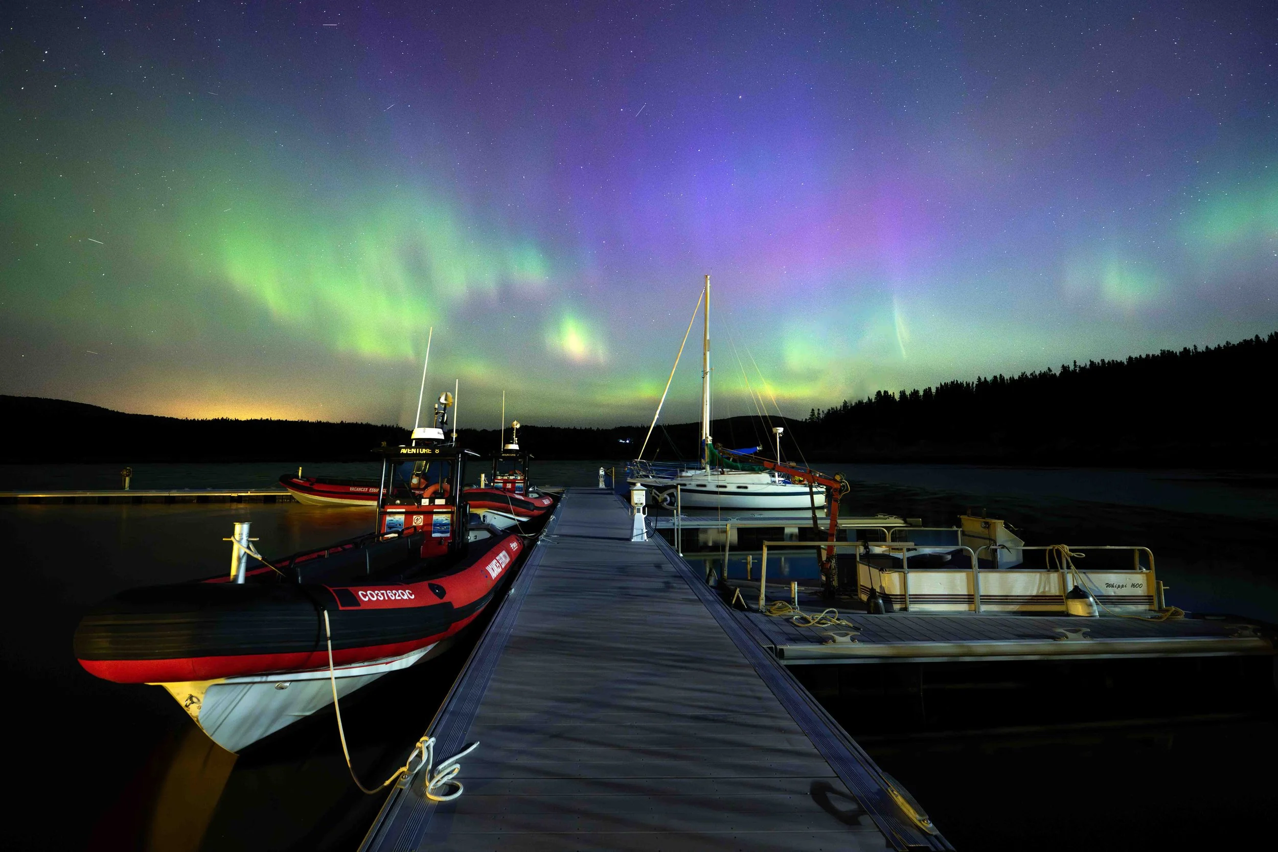 aurores boréales derrière le quai de bergeronnes au quebec
