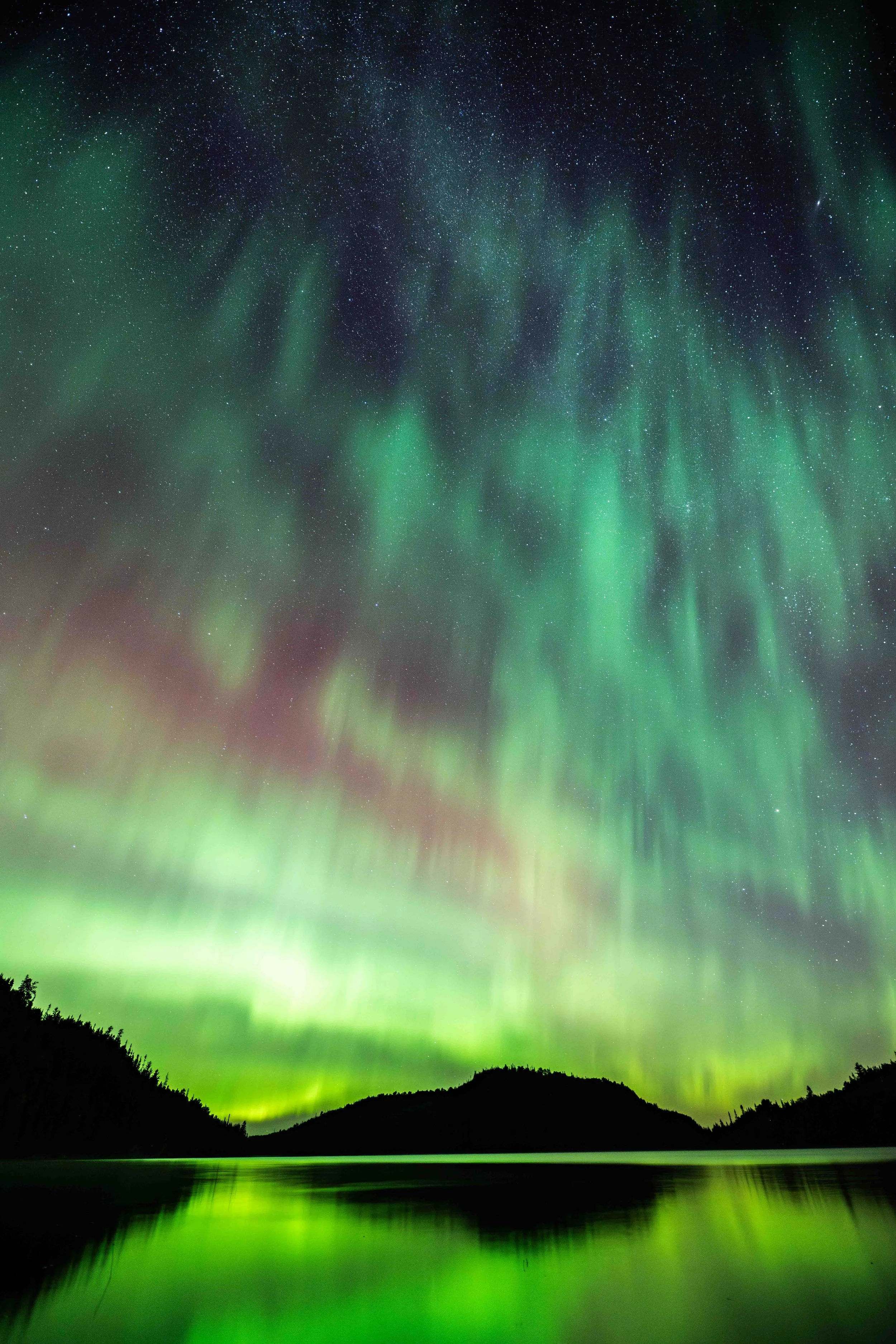 aurores boréales se reflete dans l'eau au dessus d'un lac a bergeronnes sur la cote-nord