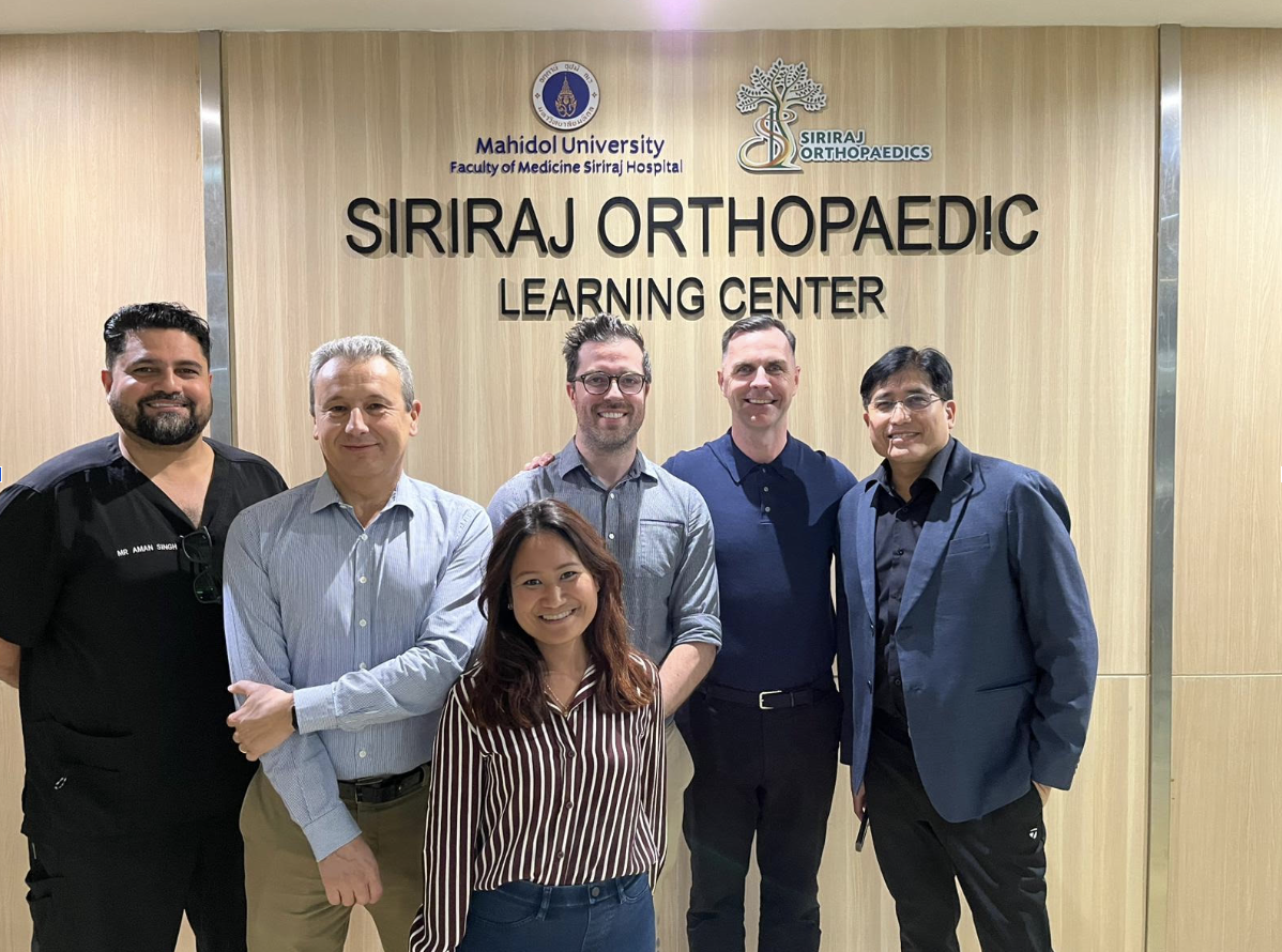 Dr Simes & fellow orthopaedic surgeons standing in front of the siriraj orthopaedic center signage