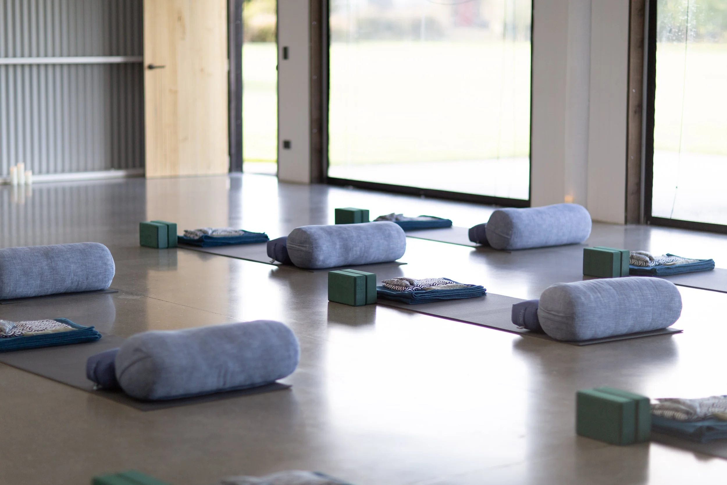 Bolsters and yoga mats prepared to welcome participants into a yoga therapy session