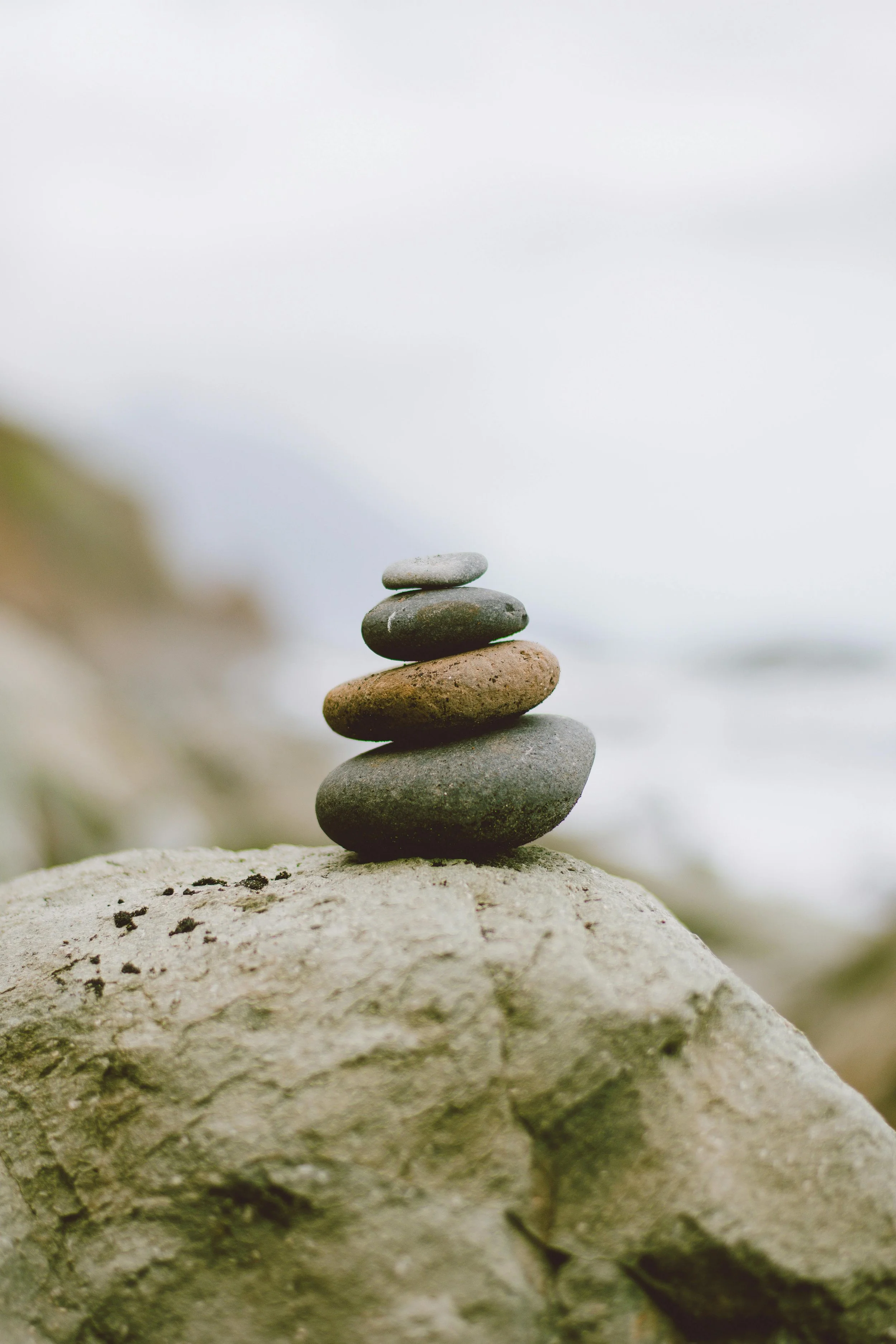 Stacked stones on the beach symbolising balance and steady progress in yoga therapy, Nelson