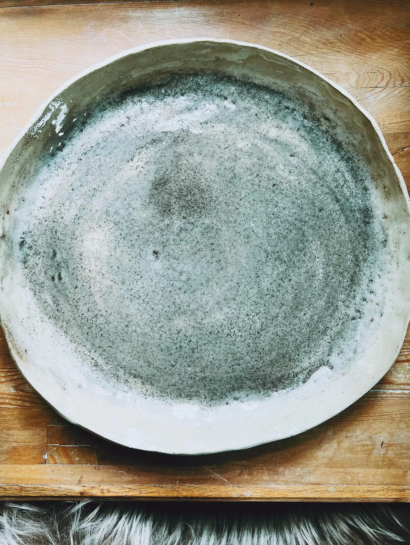 LARGE STONEWARE PLATTER

This large platter has such an interesting surface.  I rubbed some very fine black stone powder into the center. The glaze played with it; it looks almost molten, almost grey  blue in spots, almost grey green in others.  It's