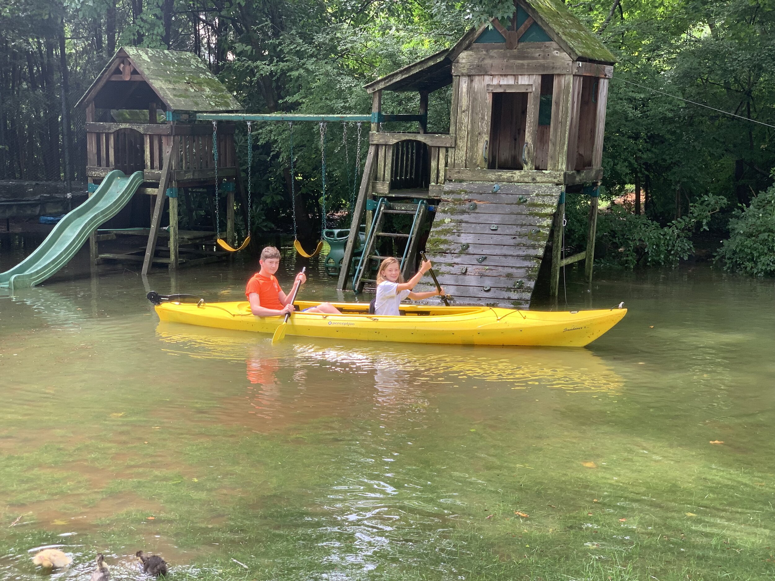 Macklin and Keira Reilly kayak past their Wright Street home’s swing-set as flooding created an impromptu waterfront. Contributed Photo