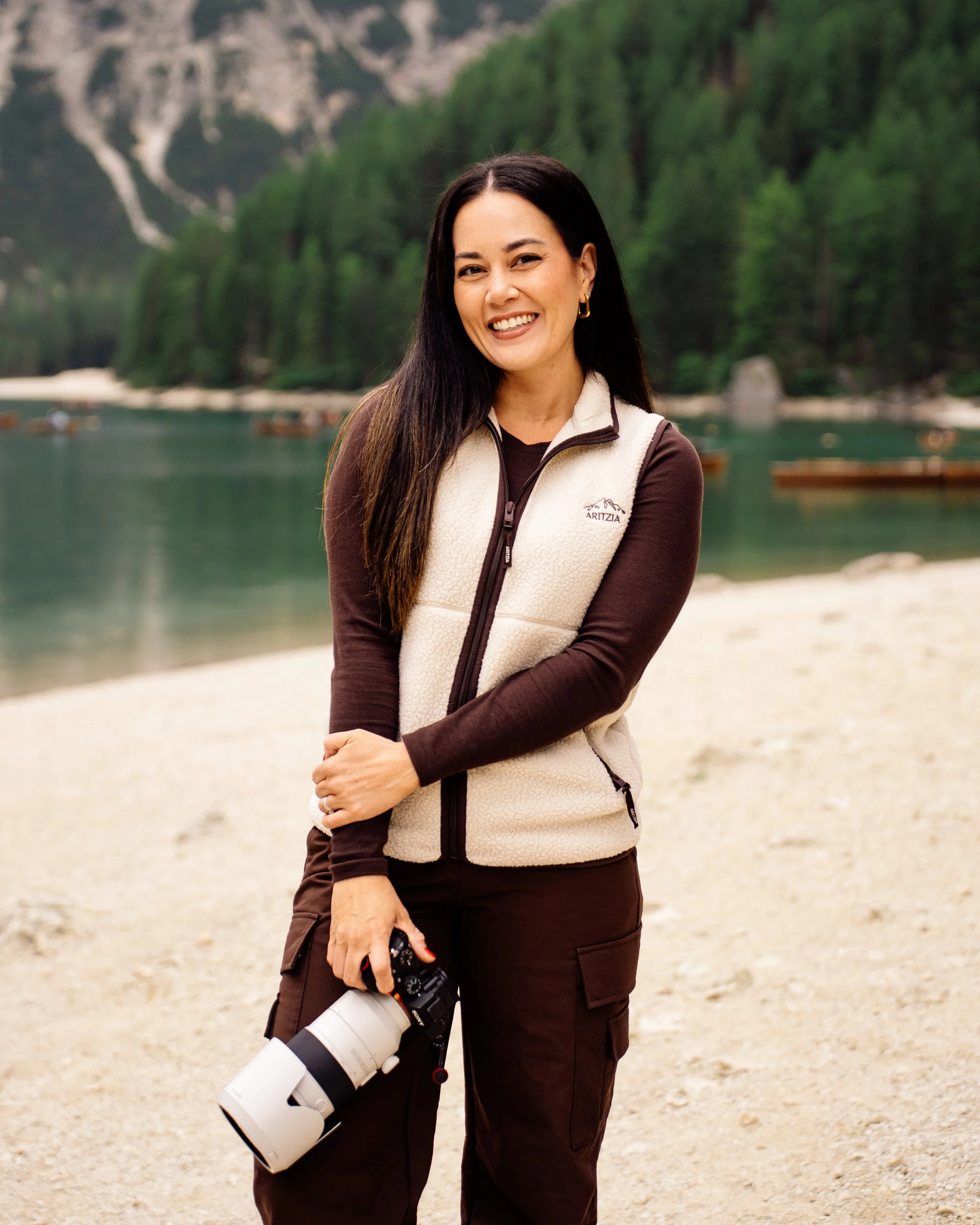 Destination wedding and travel photographer, holding a camera by the scenic Lago di Braies lake in Italy