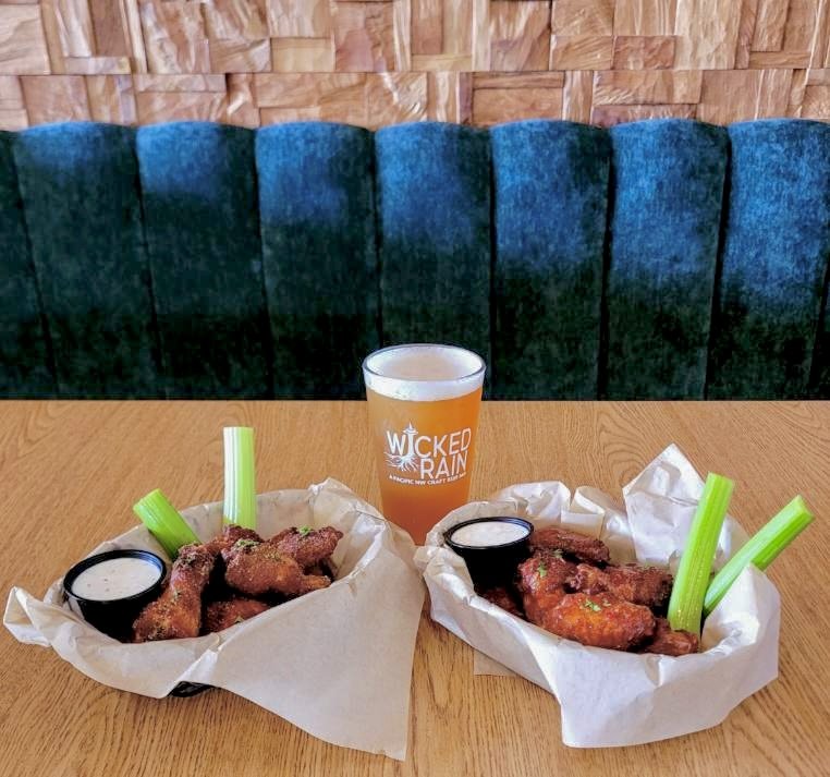 Two baskets of Wicked Wings with celery sticks, dipping sauce, beer at Wicked Rain
