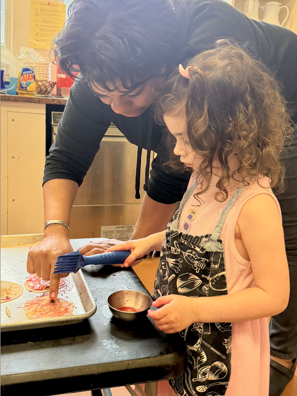 young girl cooking with teacher help, Montessori spaces
