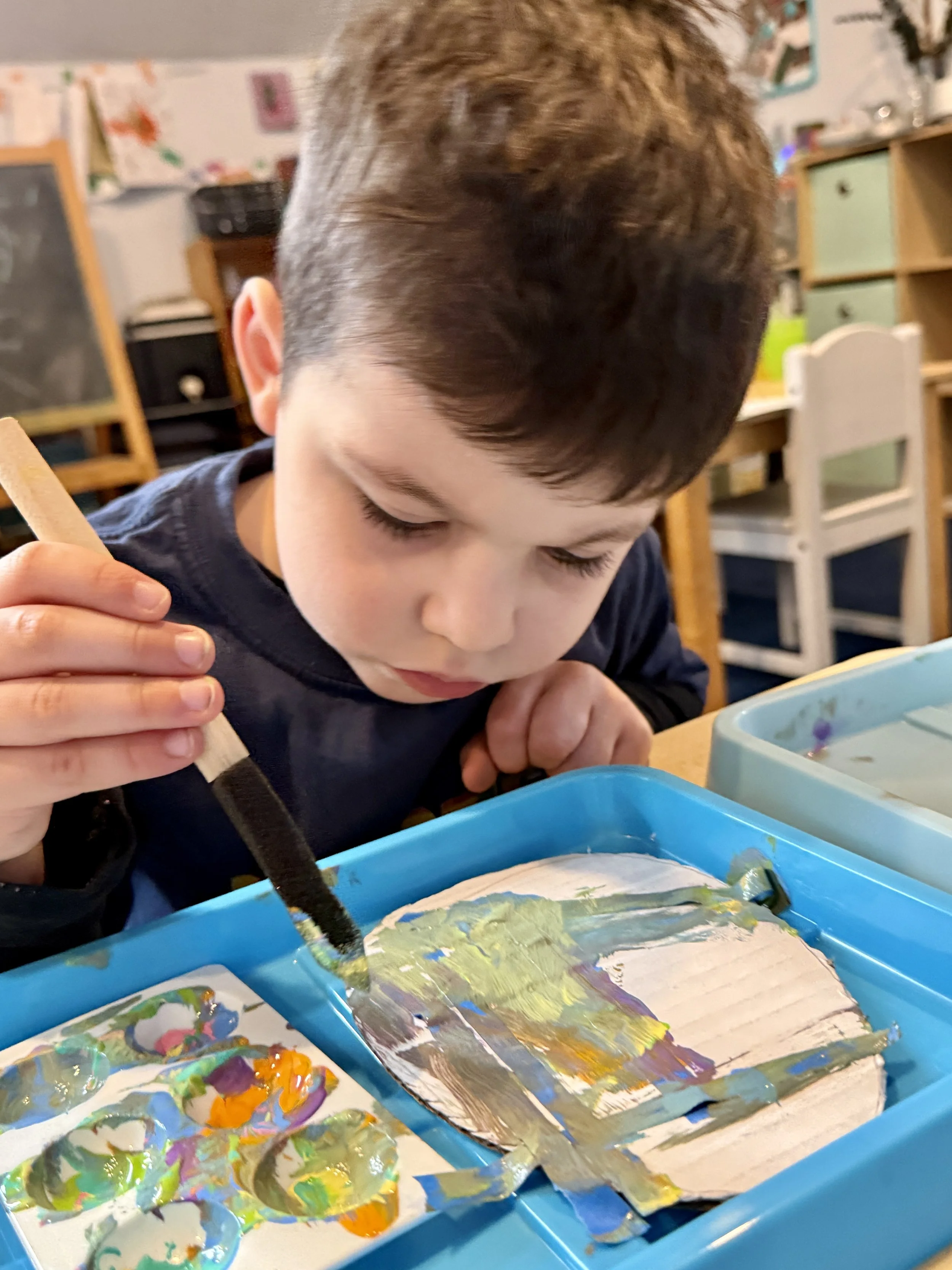young boy painting with acrylic paints, focusing, Montessori space