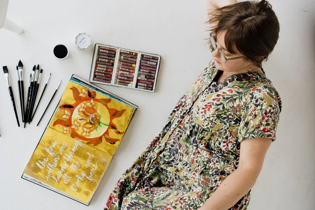 Art therapist in Colorado, Leanne Morton, with art therapy materials including paints, art journal, and oil pastels.