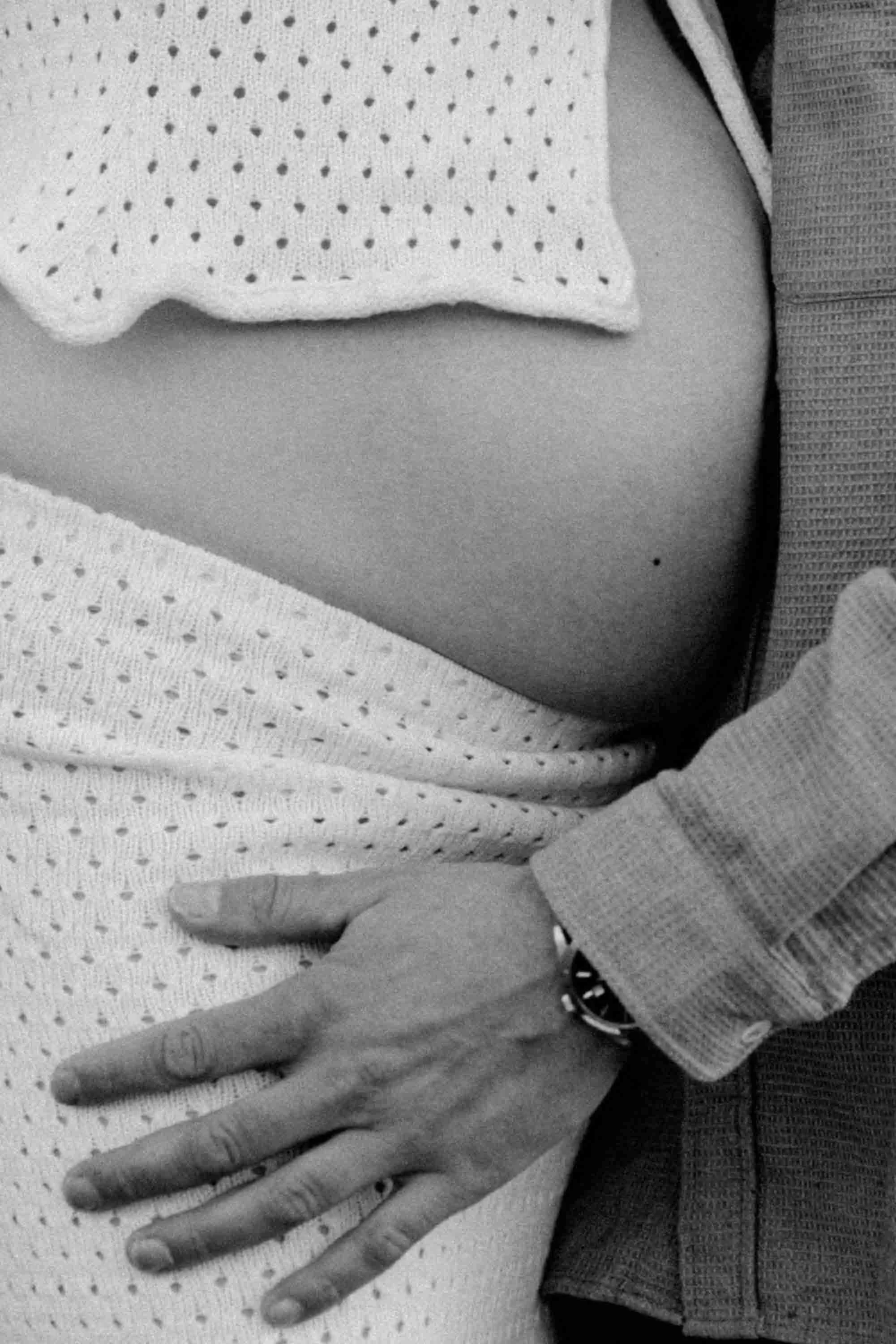 main d'un papa sur le ventre rond de sa femme
