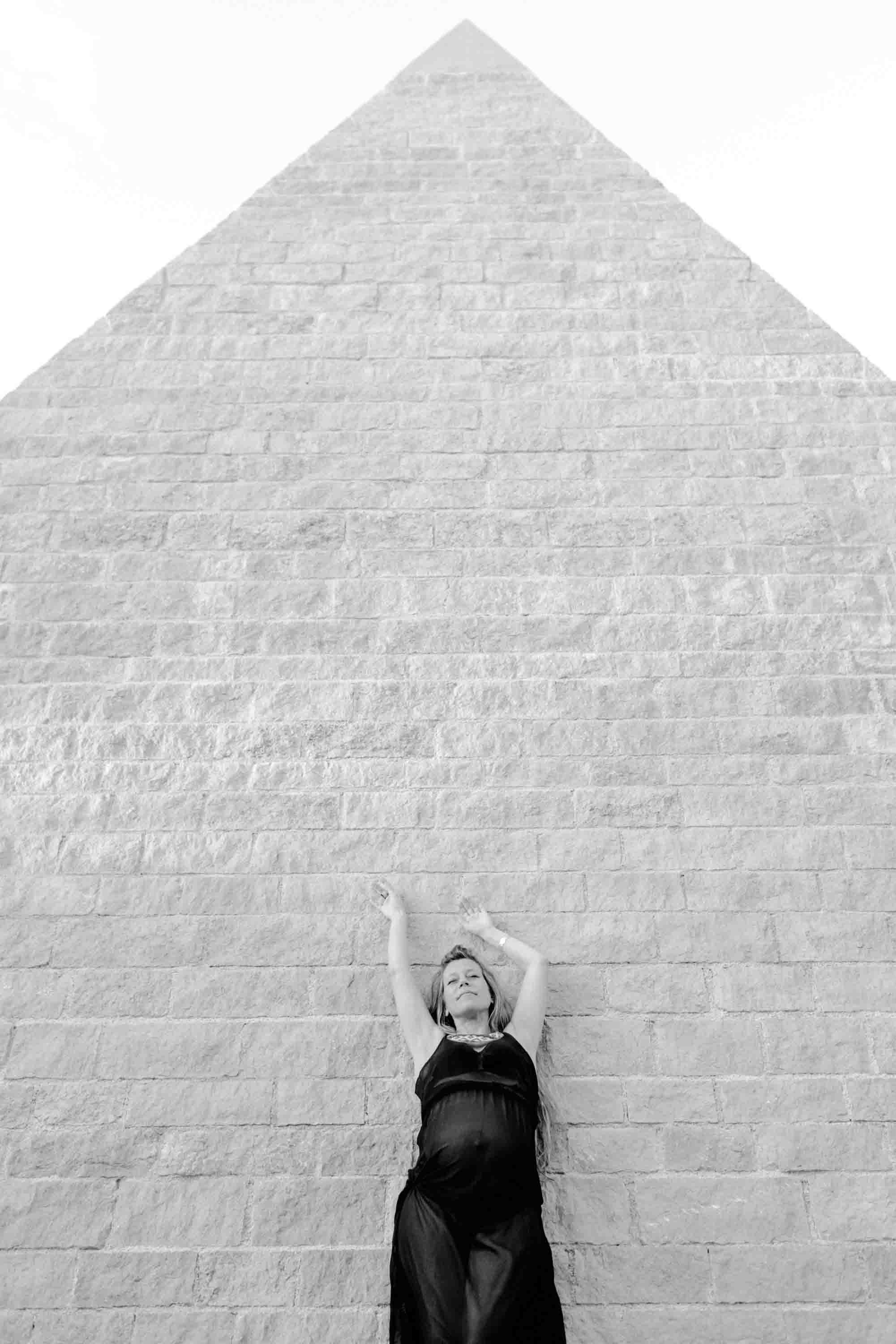 photo d'une future maman vêtue d'une robe noir près d'une pyramide