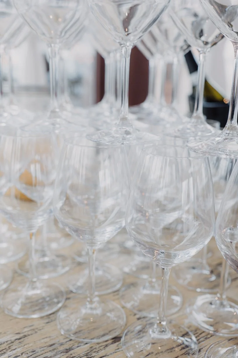 Multiple empty wine glasses arranged closely together on a wooden surface.