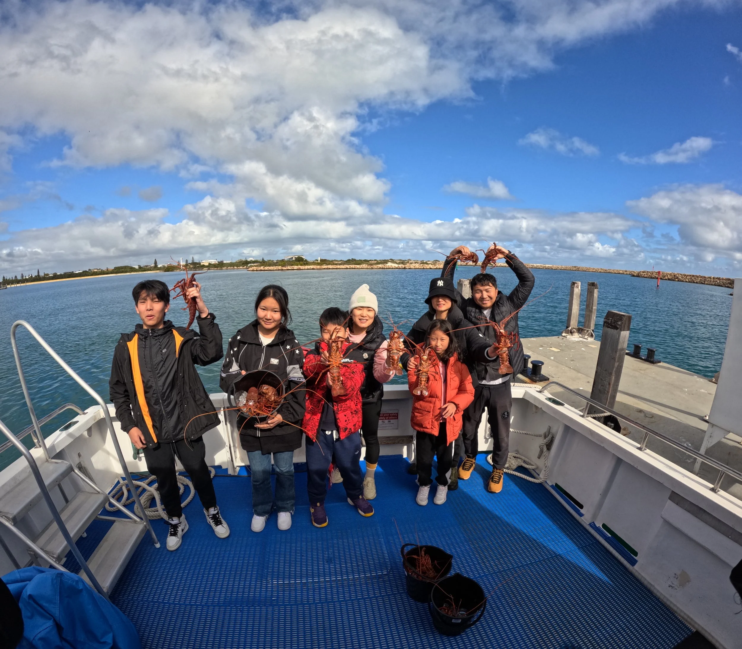 Family holding freshly caught Western rock lobsters aboard a tour boat in Jurien Bay.