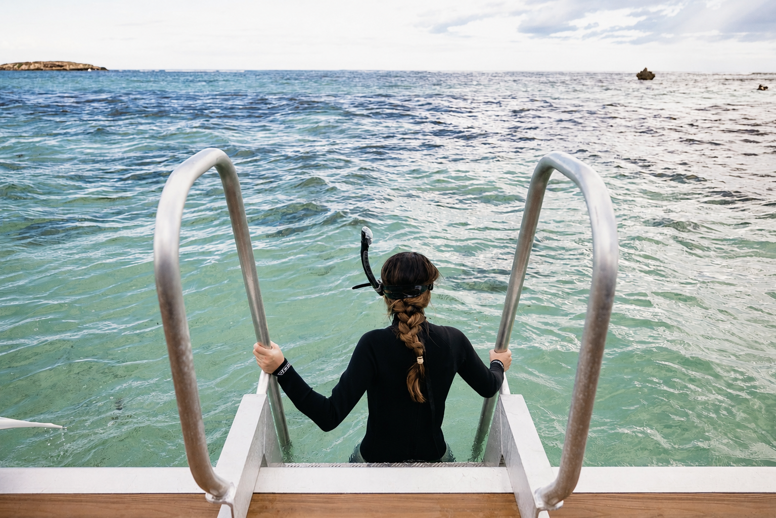 Guest using the easy-access swim ladder on a Jurien Bay Oceanic Experience vessel in Jurien Bay, Western Australia.