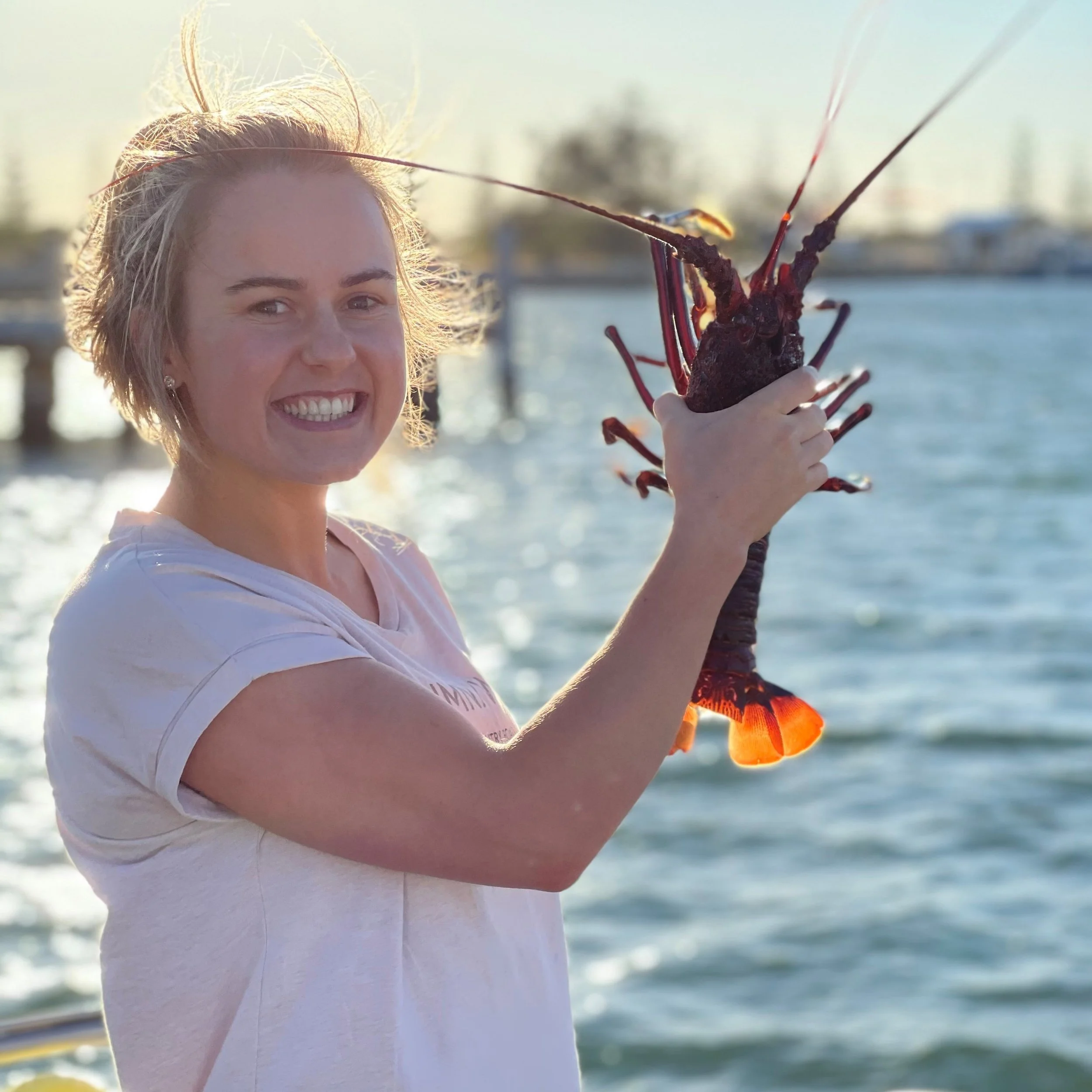 Person holding a Western rock lobster at Jurien Bay after a lobster catching tour.