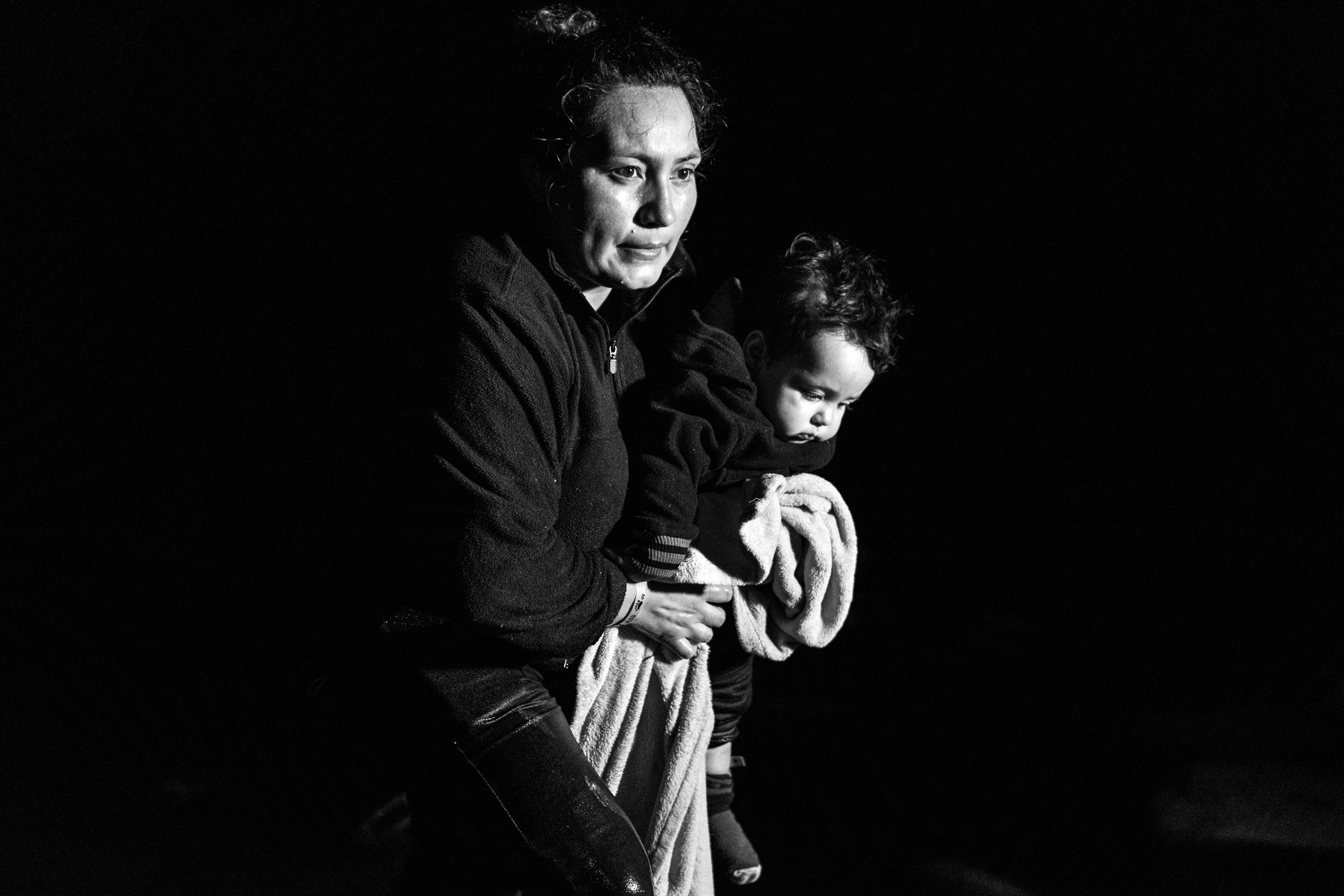 A mother carries her young child across the Rio Grande River in Roma, Texas. 