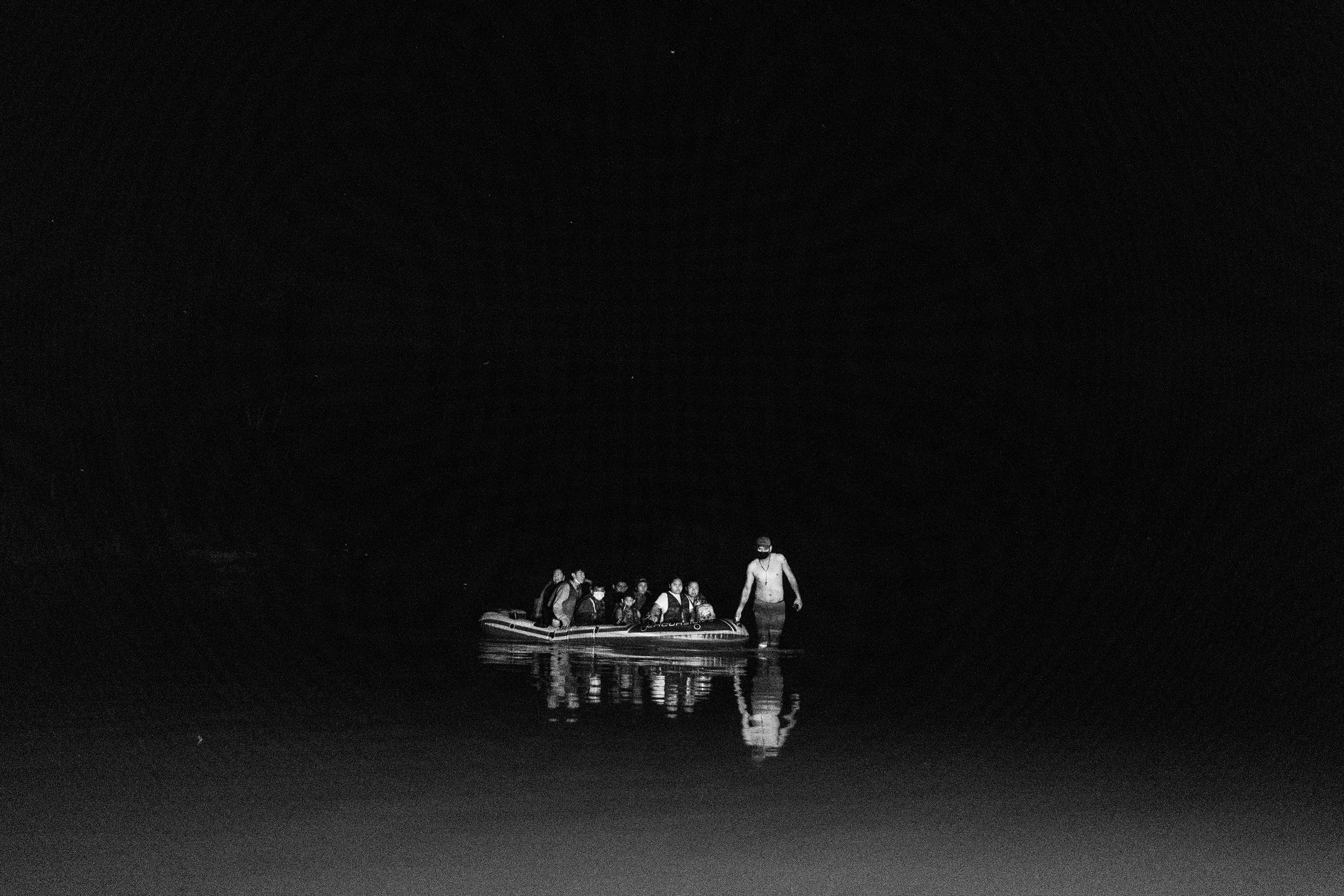 A raft of America-bound migrants wade in the darkness on the Rio Grande River.