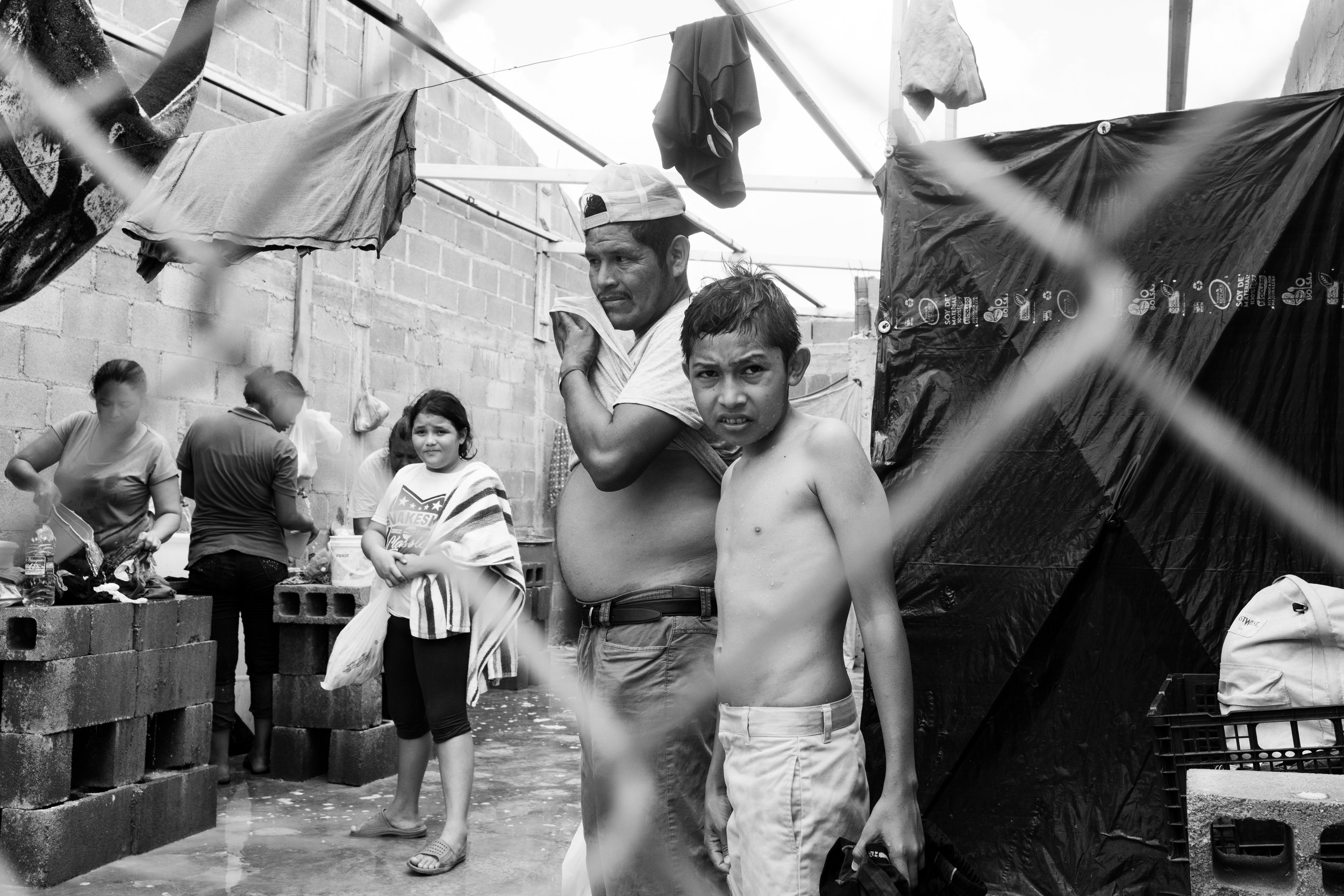  A young boy looks out of the make-shift shower facilities at the migrant camp in Reynosa, Mexico. 