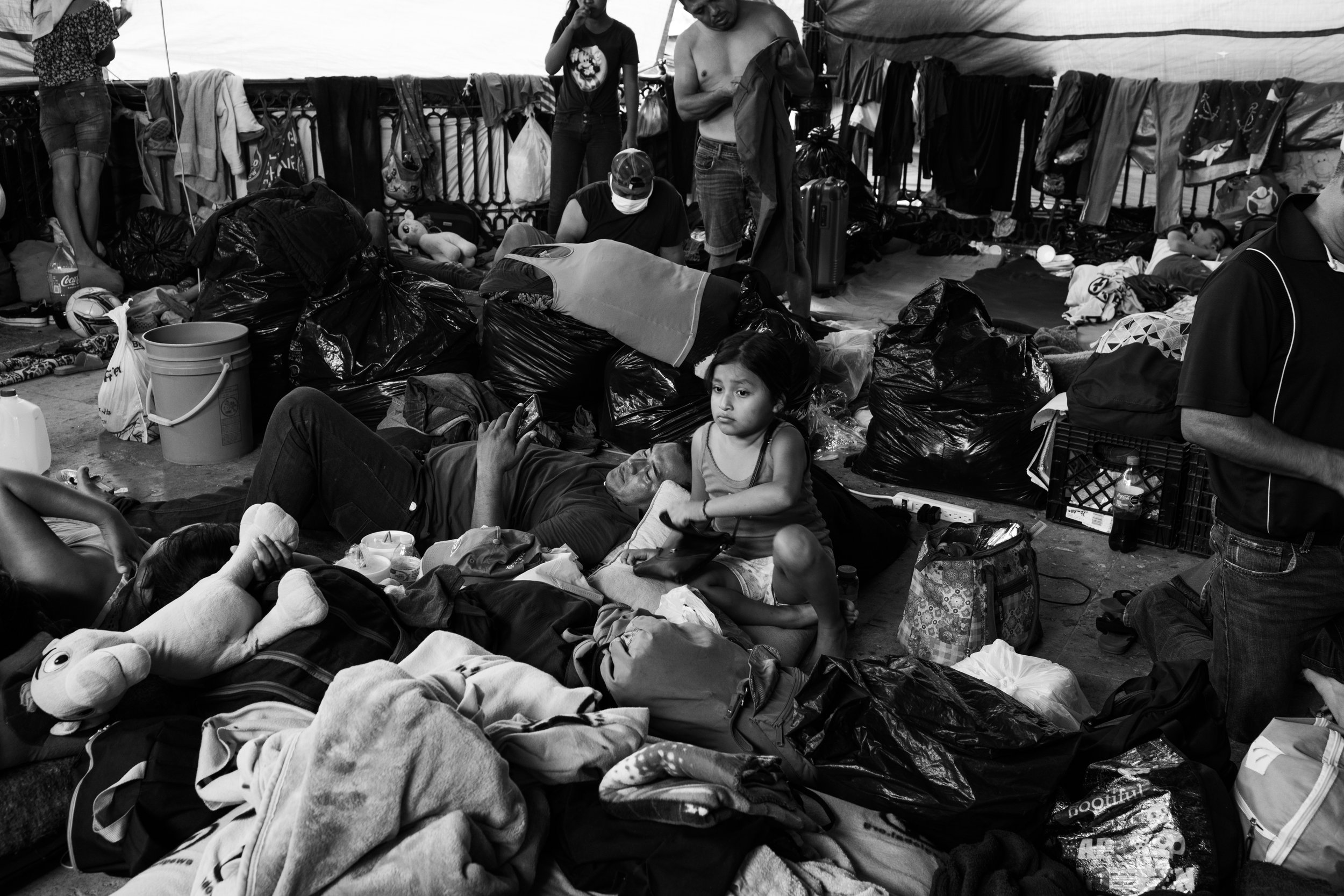  A young girl sits in an overcrowded sleeping space in Reynosa, Mexico. 