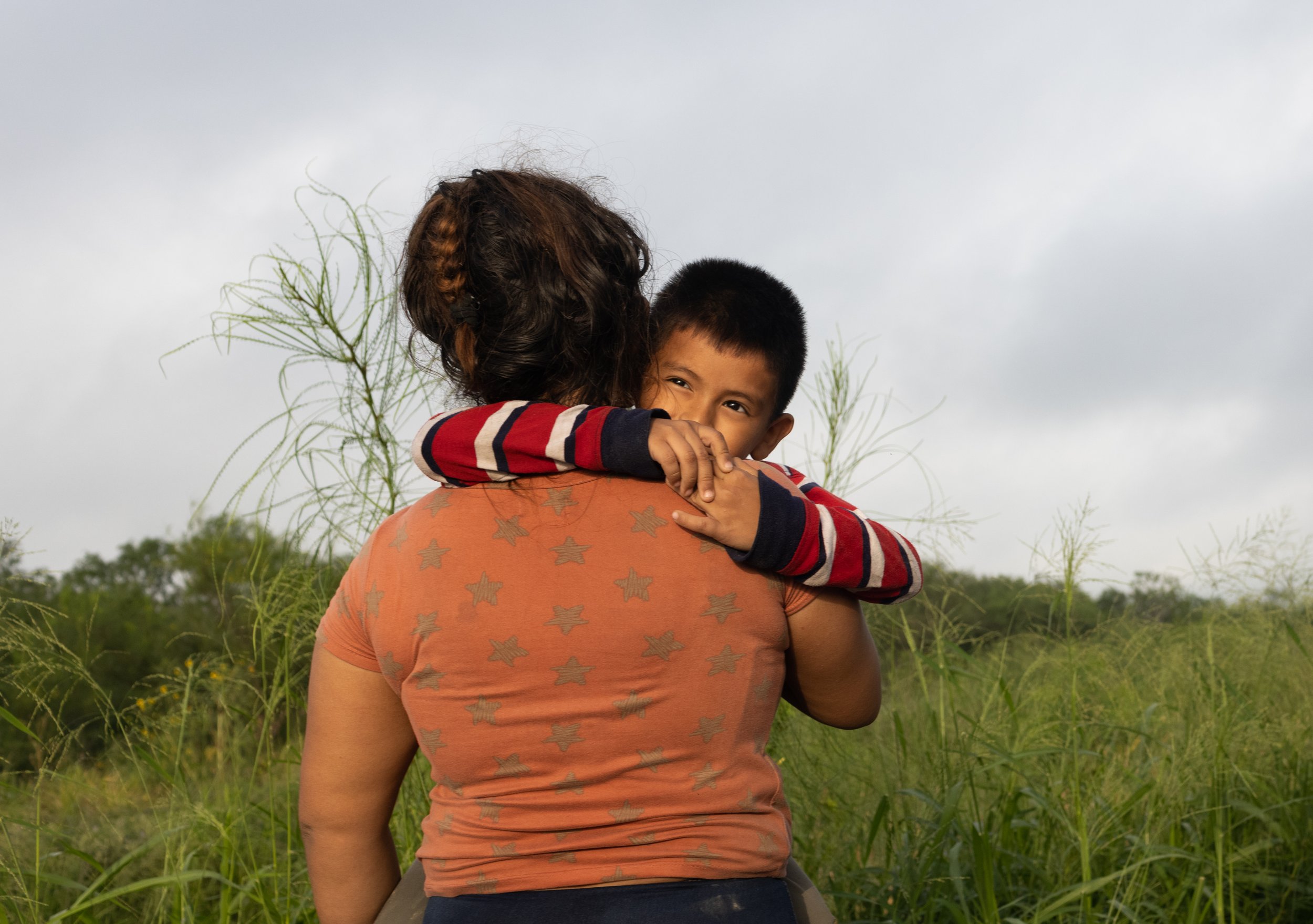  A mother migrant holds her son as they wait to be process by Border Patrol agents after they arrived in La Joya, Texas. 