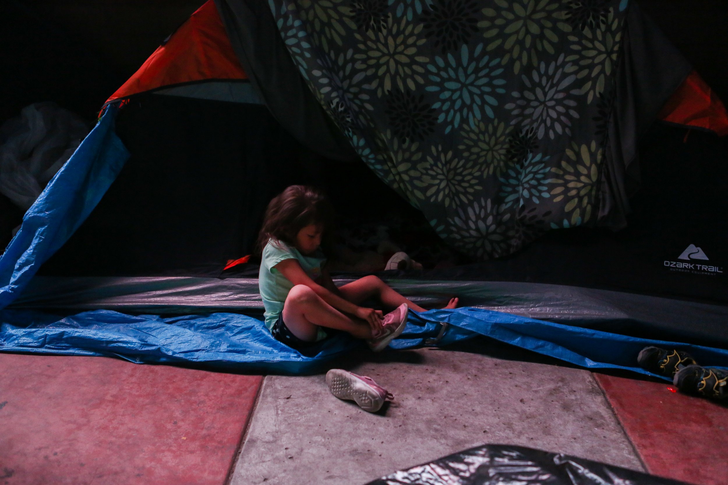  A girl puts on her shoes outside her tent in Tijuana, Mexico. 