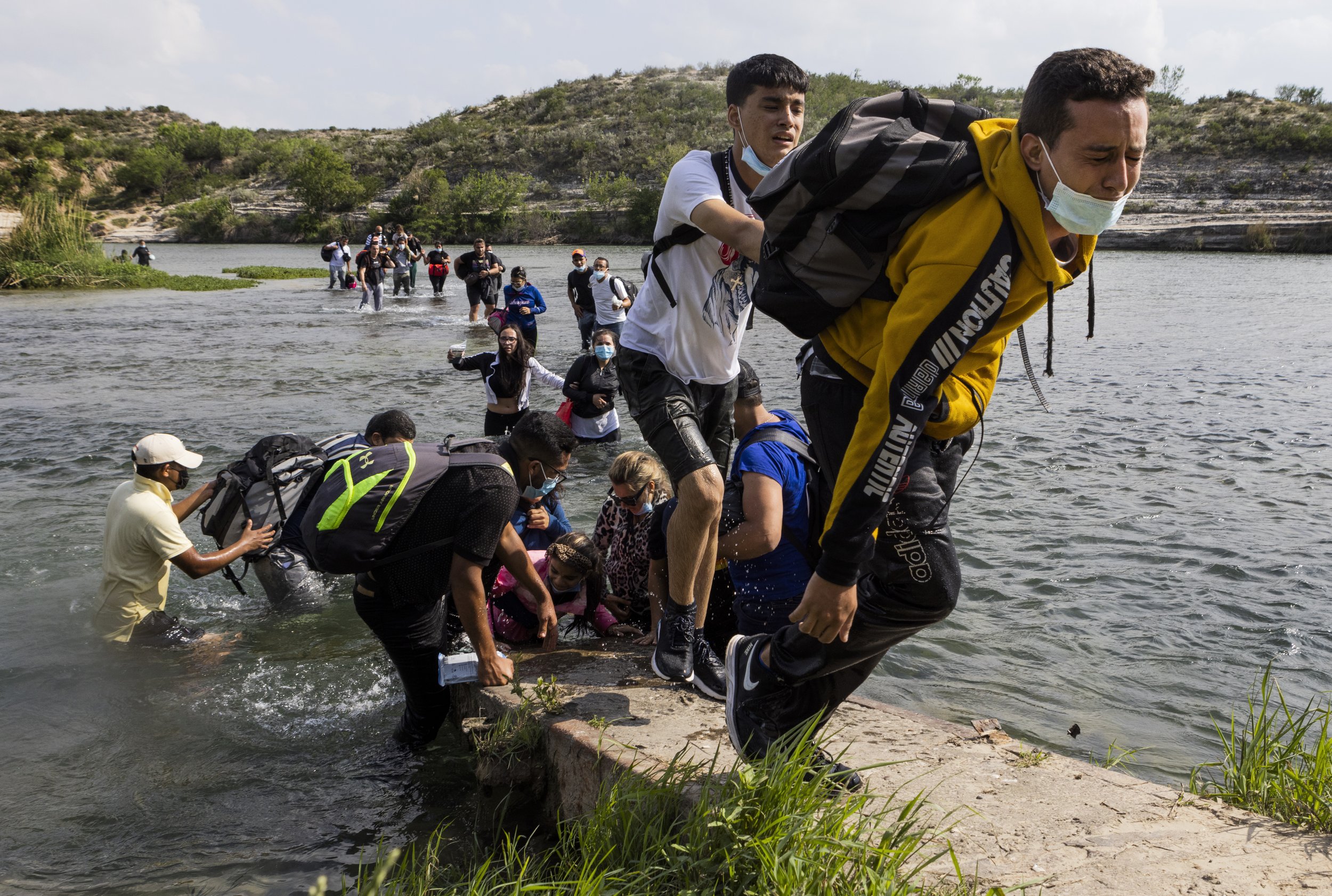  A man leads the train of  migrants helping each other cross the Rio Grande River in Del Rio, Texas. 