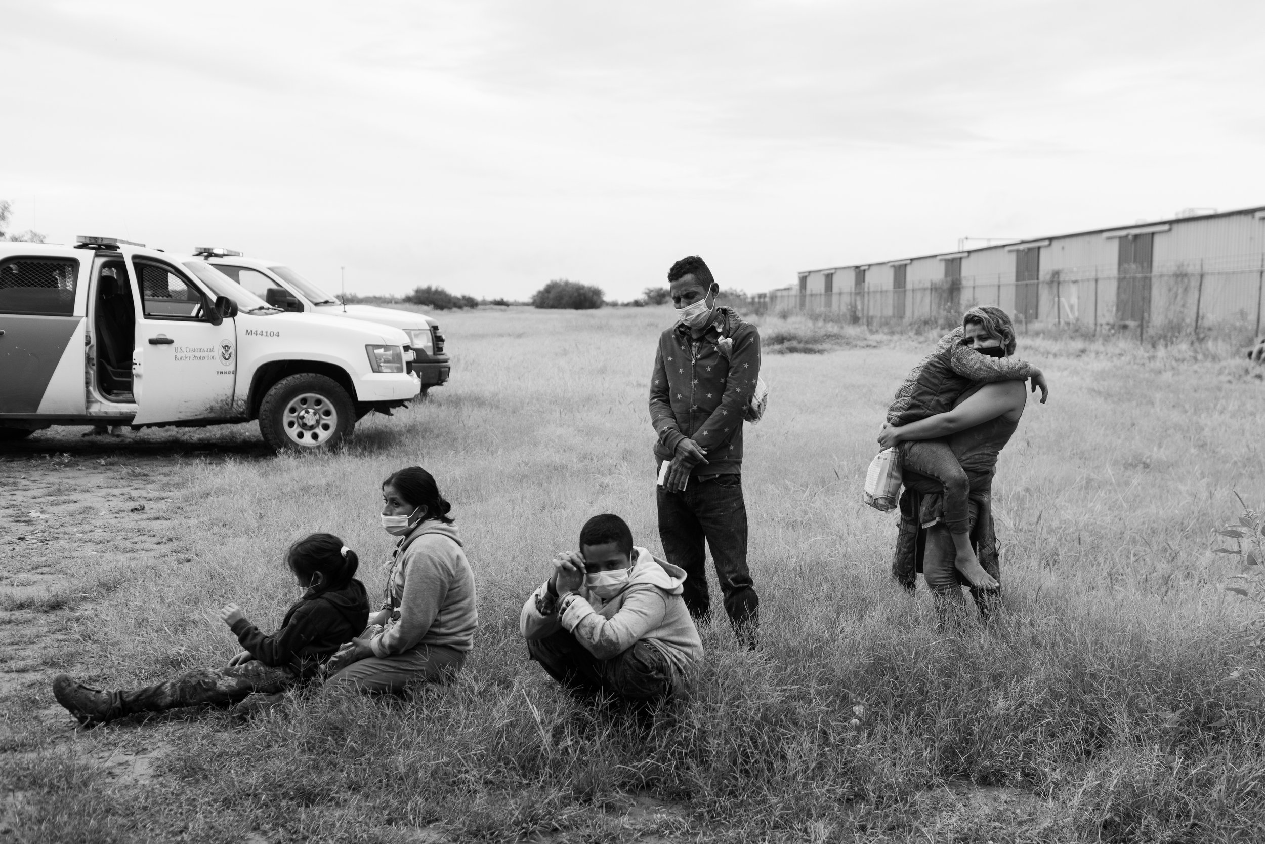  Newly arrived migrants wait in the grass in La Joya, Texas to be processed and transported by U.S. Border Patrol. 