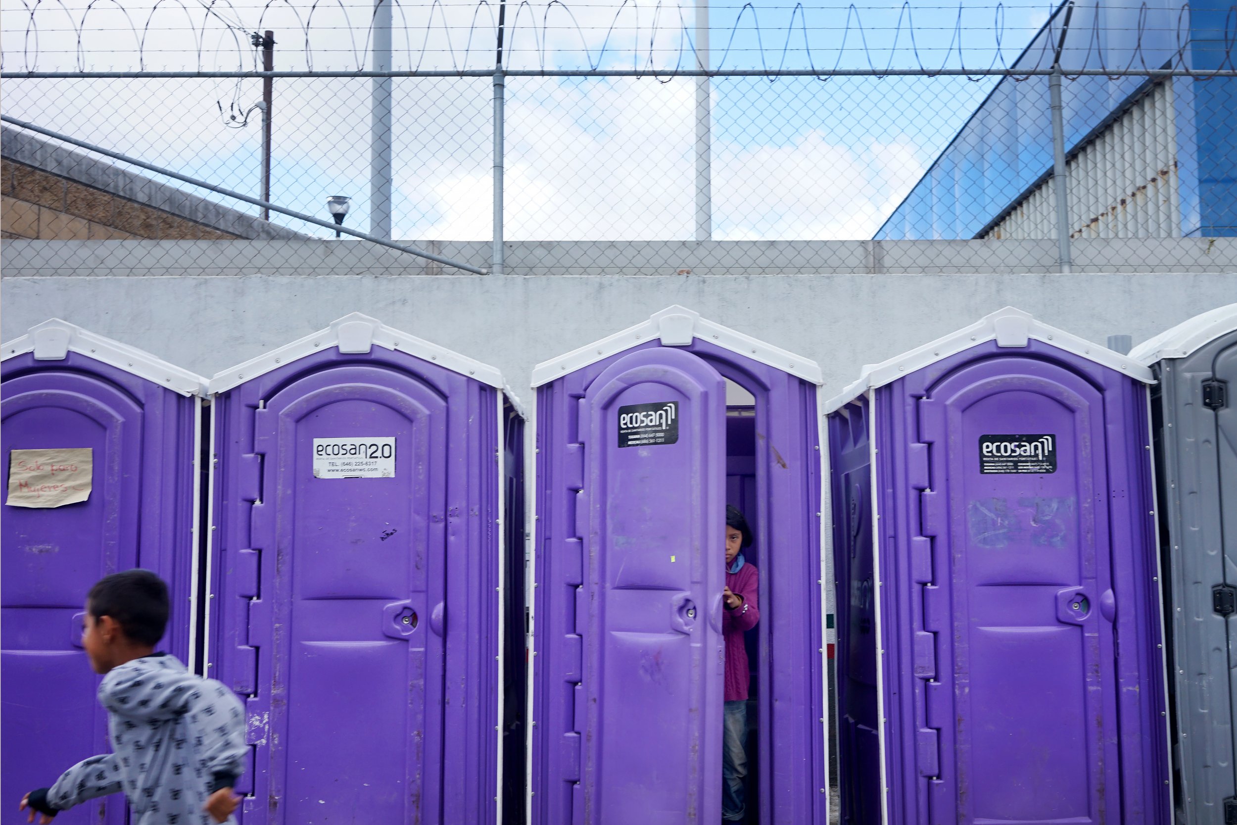  A girl exists one of the donated bathrooms at El Chaparral in Tijuana, Mexico. 