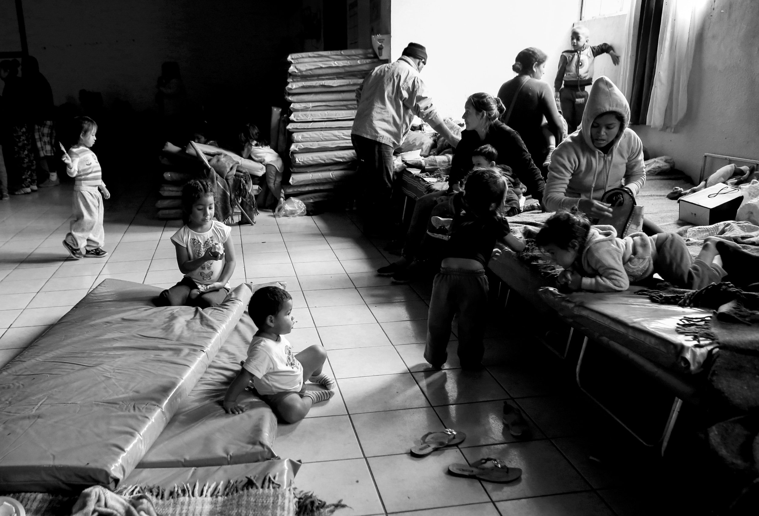  Children play on mattresses and cots in the main room of my the shelter. 