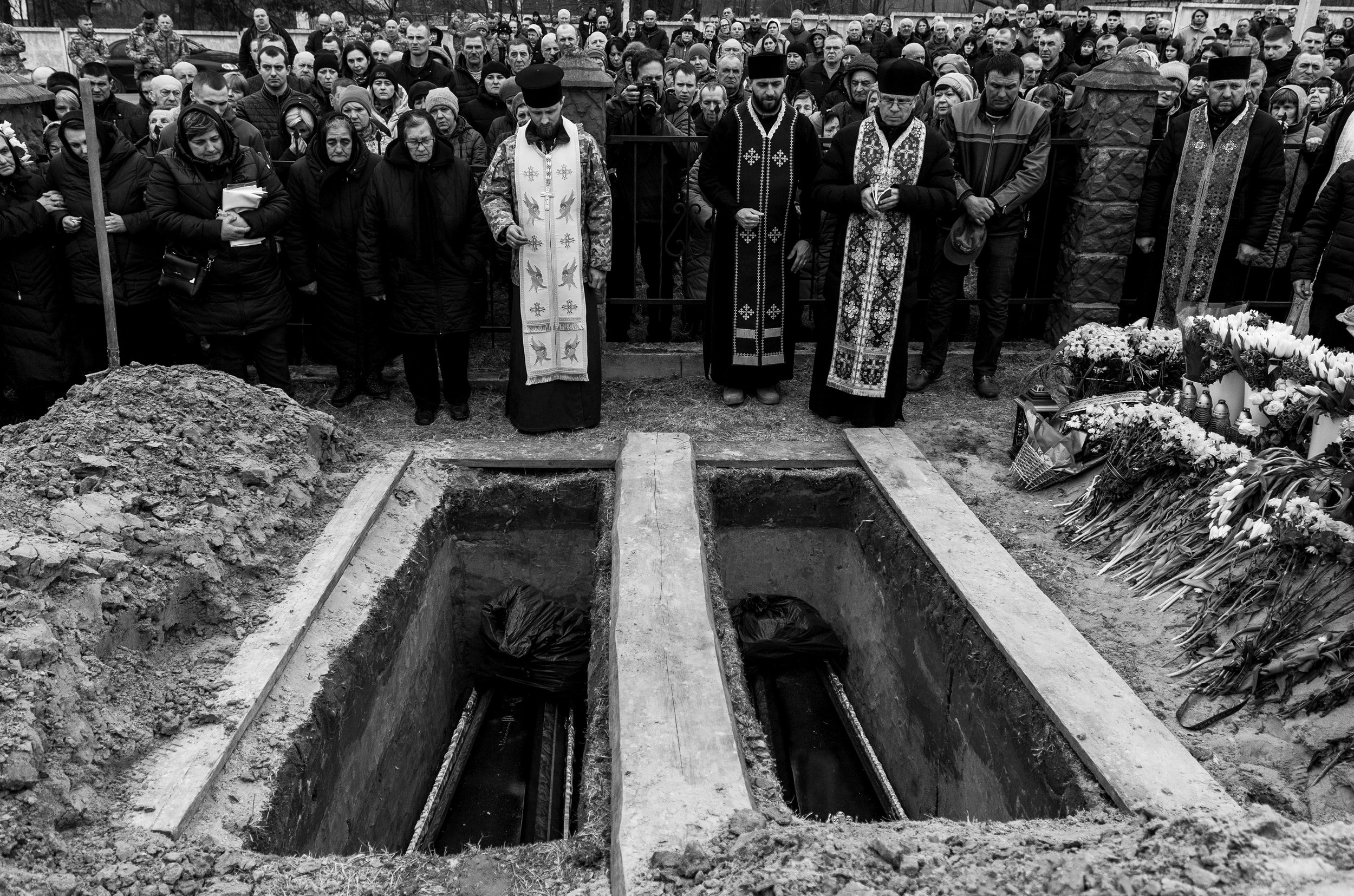  Family and town members gather with the local priests at the gravesite of Mykola Dmytrovych and Roman Fedorovich who were killed in a Russian airstrike that hit a military base in Starychi, a small village on the outskirts of Lviv, Ukriane. 