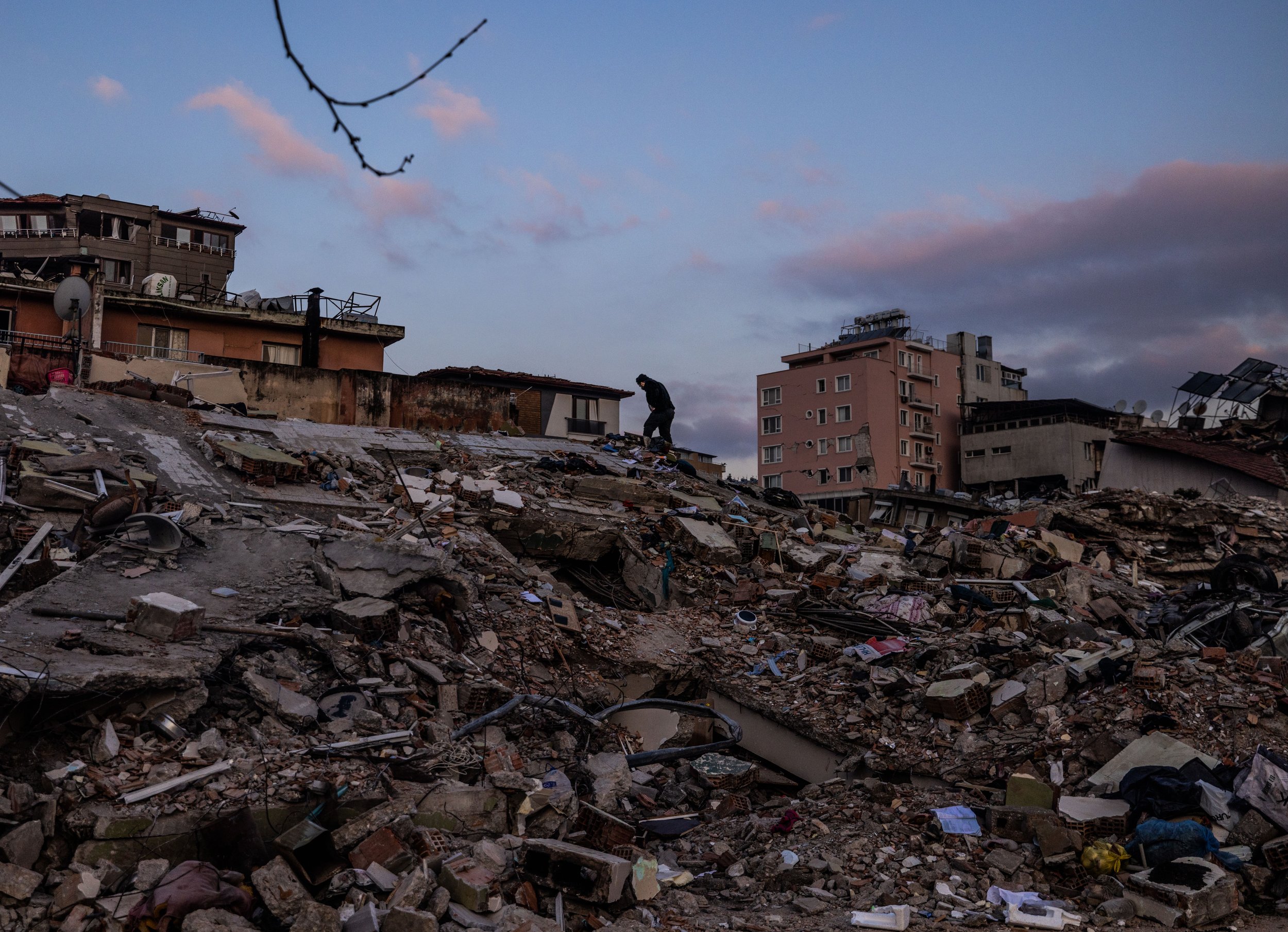  A man climbs a mountain of debris in Hatay, Turkey on February 11, 2023. 